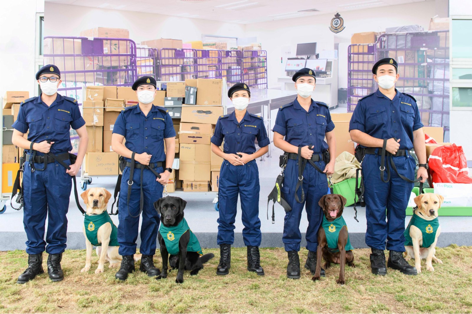 圖示海關搜查犬課監督黃惜忻（中）與四隻槍械搜查犬（左起）Nicky、Wrangler、Quick和Gasper及牠們的領犬員合照。（政府新聞處圖片）
