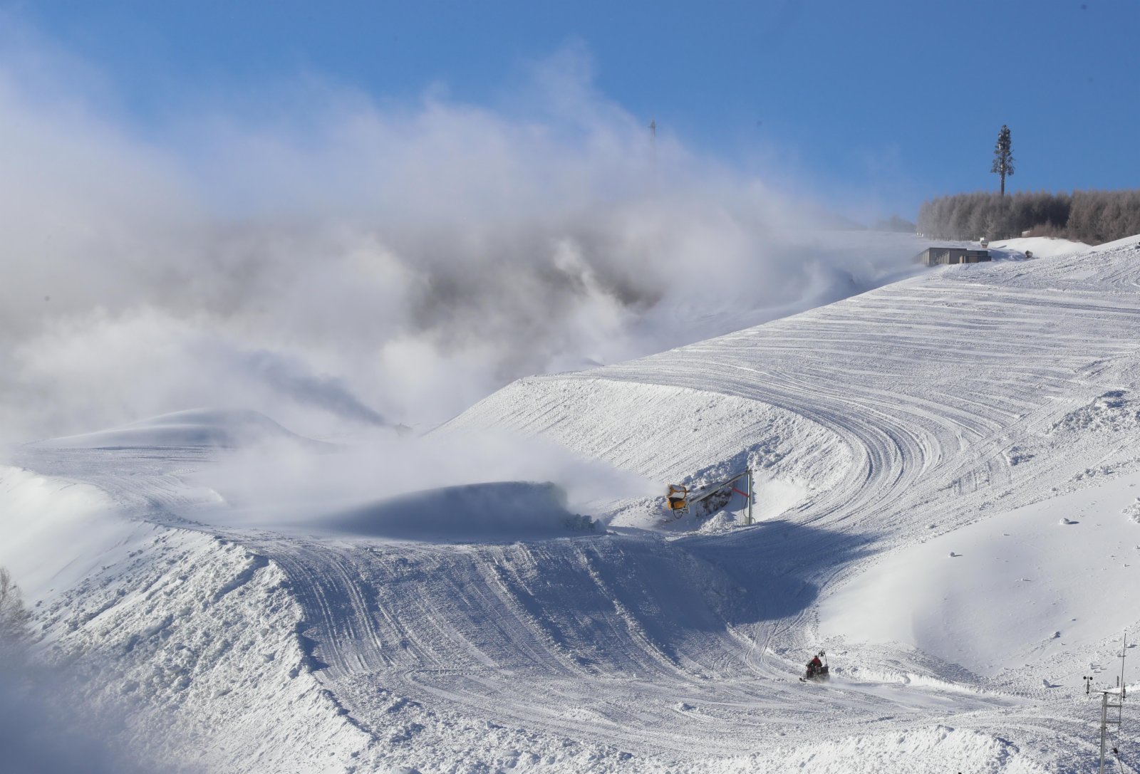 12月17日，工作人員駕駛雪地摩托從雲頂滑雪公園的一條賽道上通過。（新華社）
