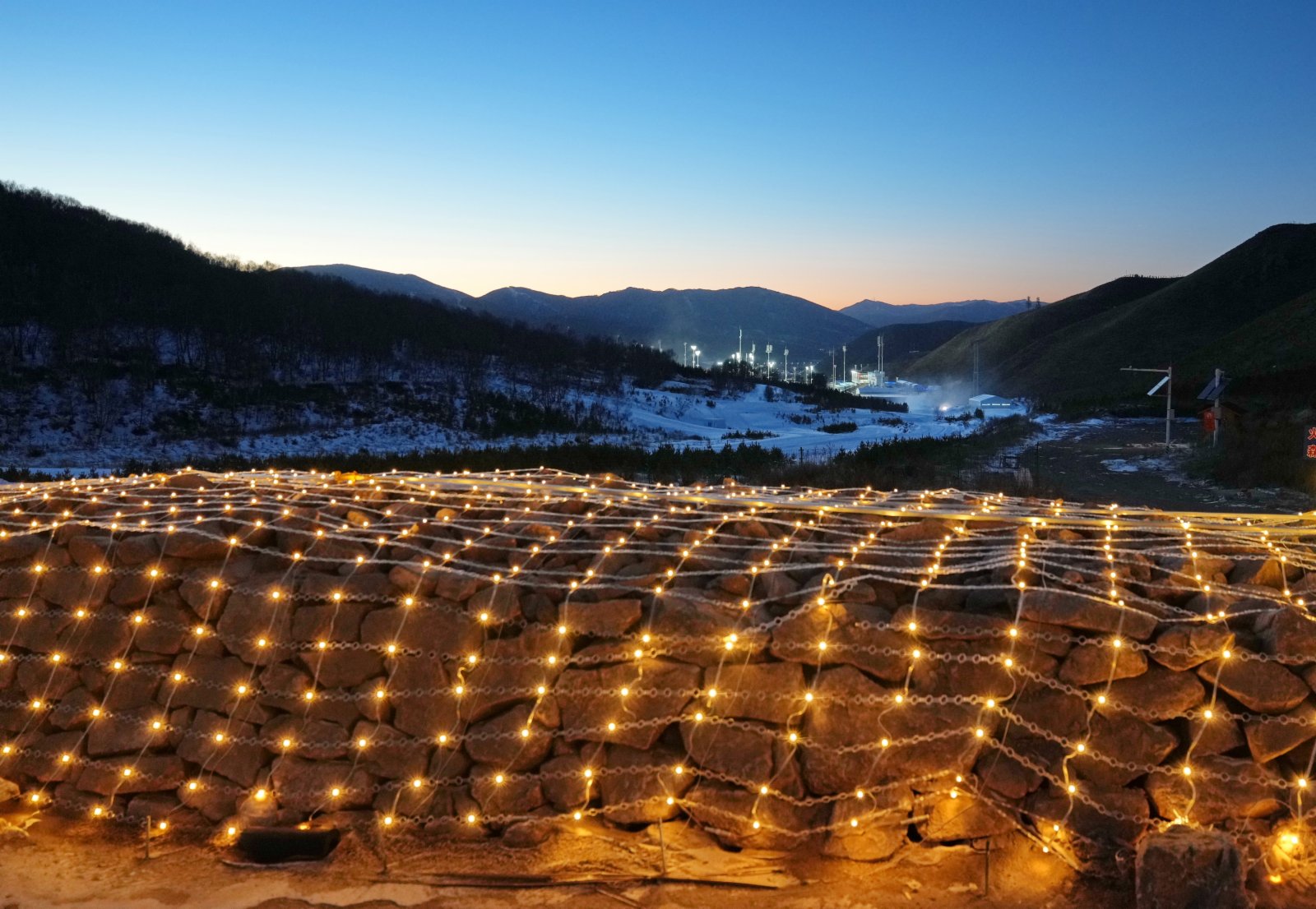 這是2021年12月30日拍攝的崇禮長城景觀展示亮化工程現場，遠處為國家越野滑雪中心。（新華社）
