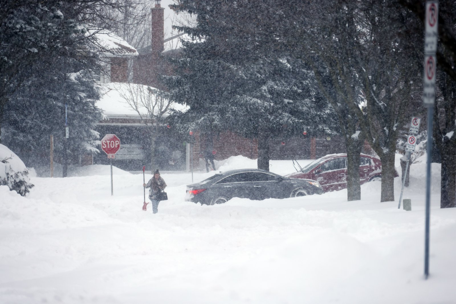 多倫多一位手持雪鏟的居民行走在積雪的路面上。 （中新社）
