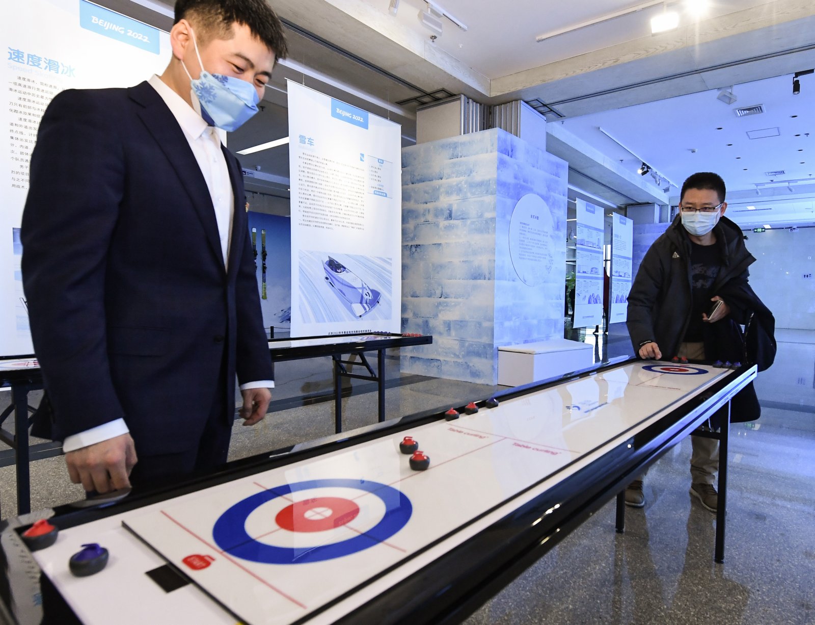 1月20日，一名嘉賓（右）在展覽上體驗桌上冰壺。（新華社）