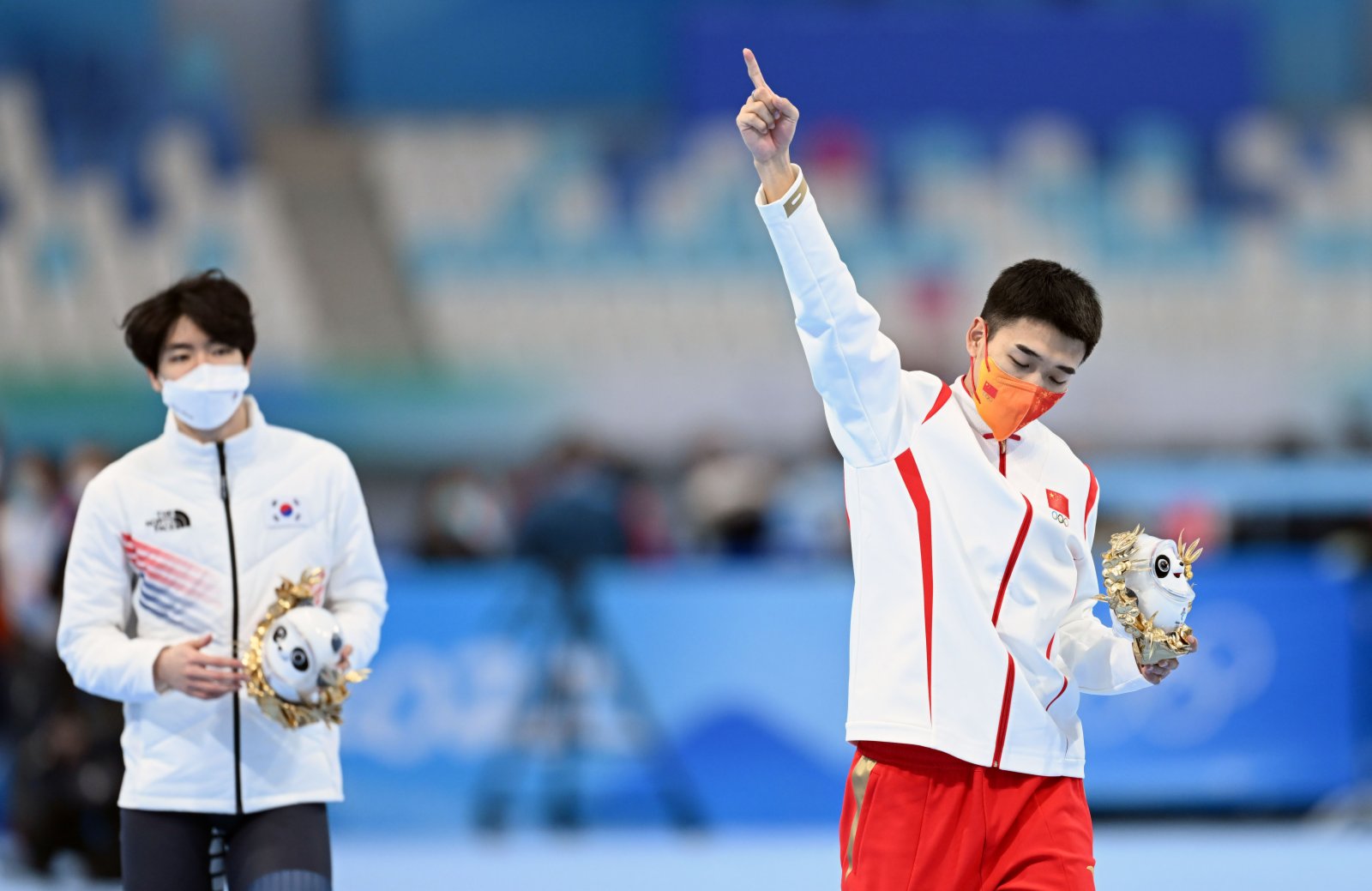 中國選手高亭宇（右）在頒發紀念品儀式上，高舉手指，表示自己是第一名。