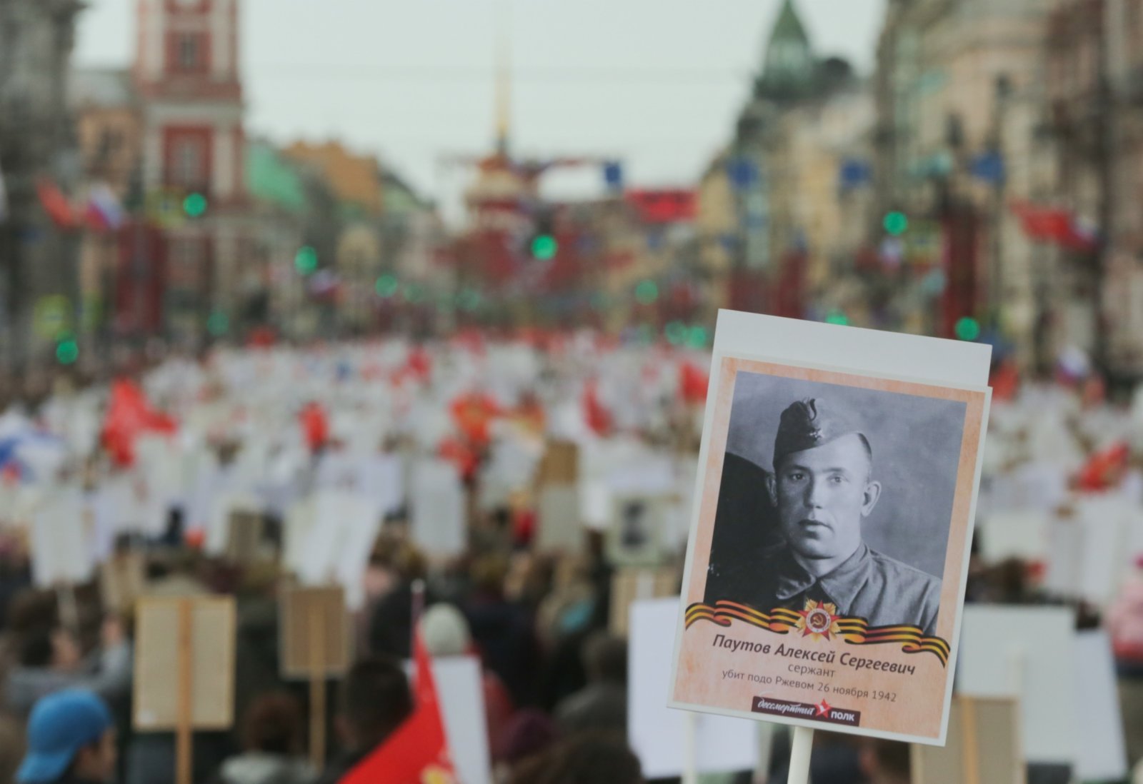 俄羅斯聖彼得堡民眾手持先輩照片參加「不朽軍團」遊行。（新華社）
