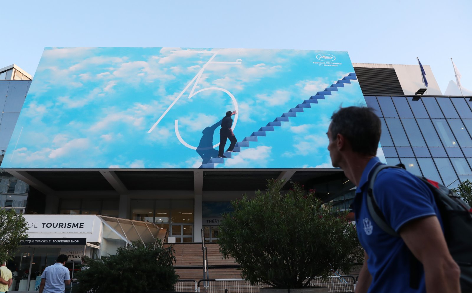 在法國南部海濱城市戛納，一名行人路過電影宮外的巨幅海報。