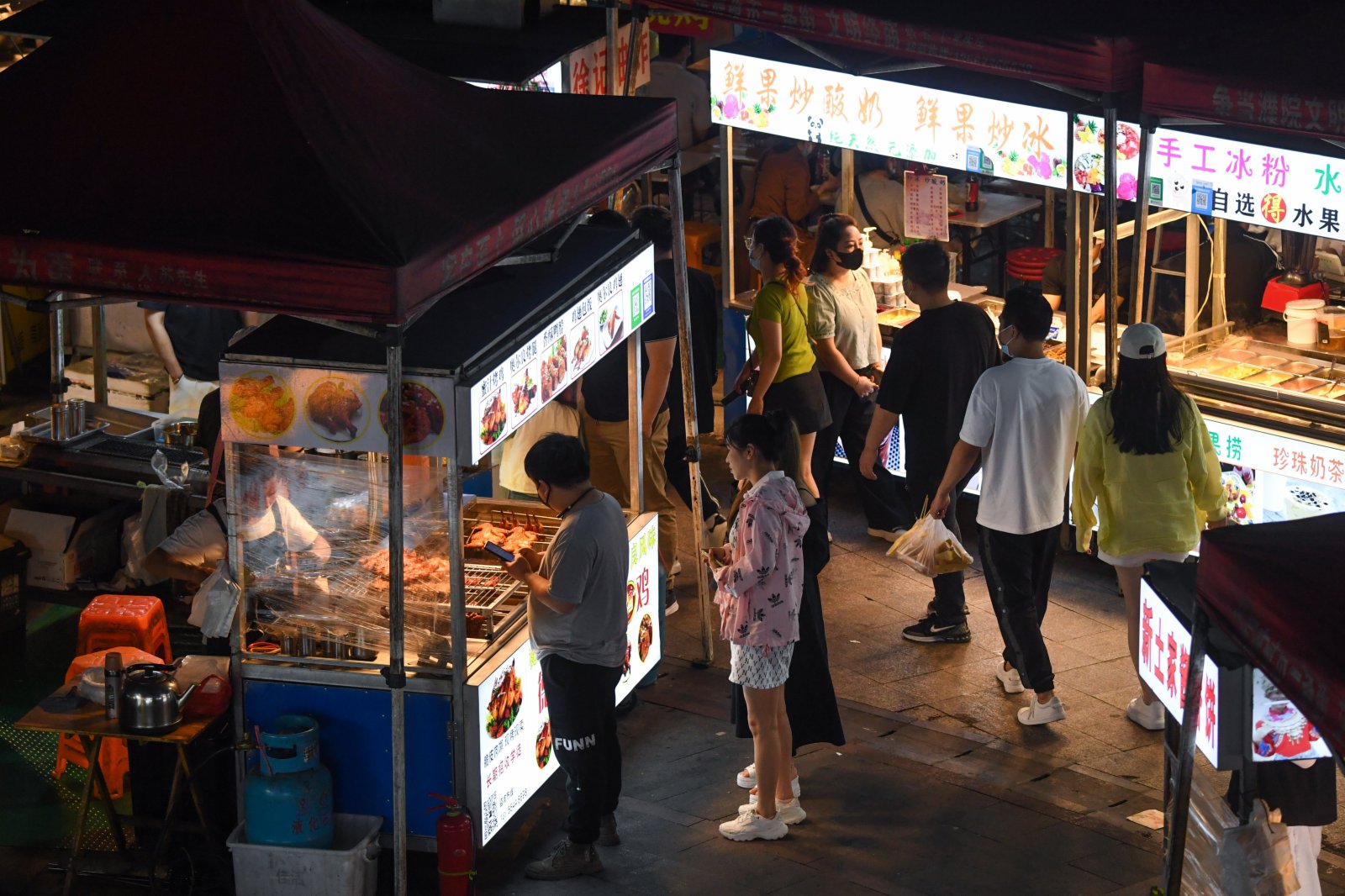 5月17日，居民在濮院鎮佳源夜市的小吃攤挑選美食。（新華社）