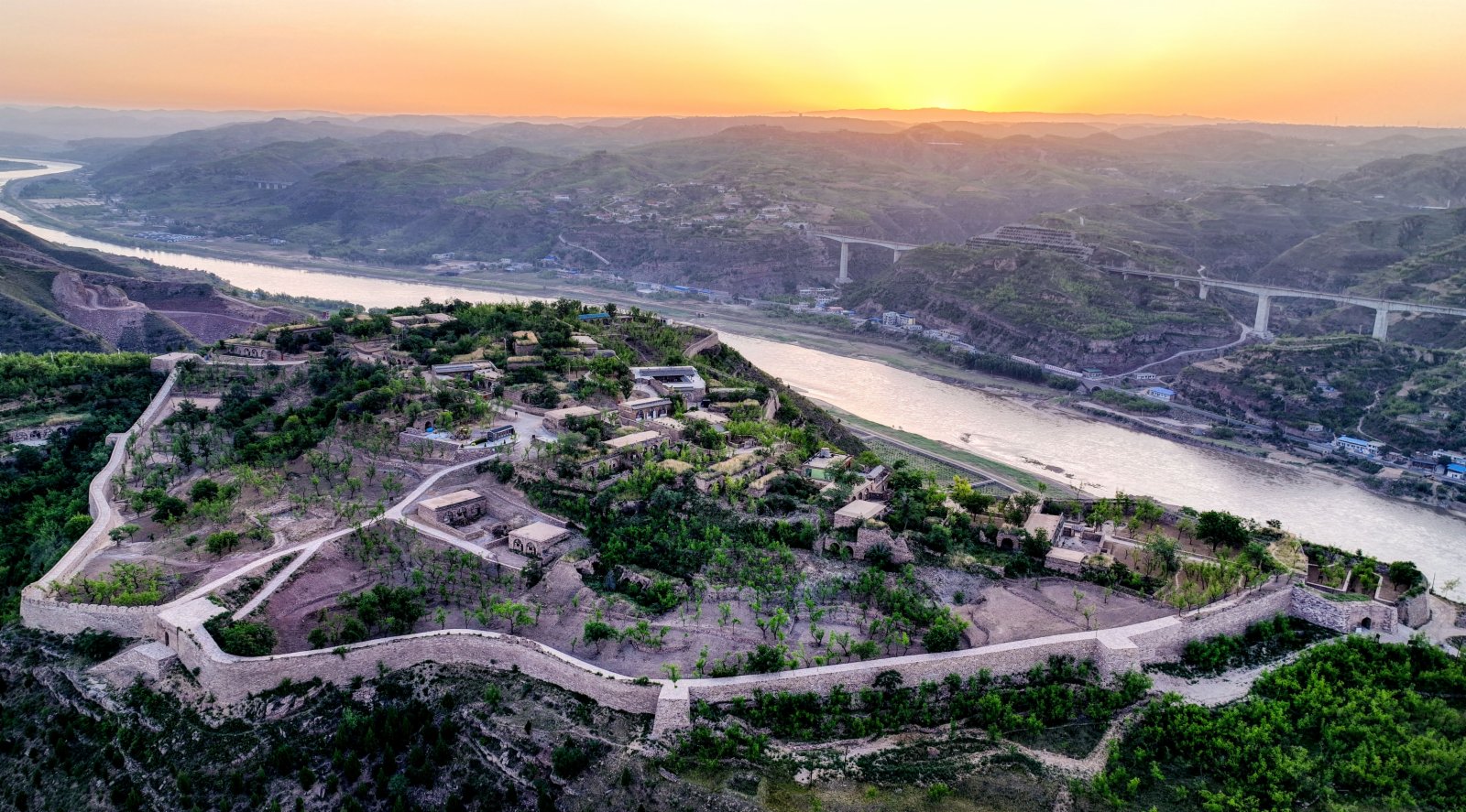 這是6月8日拍攝的朝霞映照下的吳堡石城（無人機照片）。（新華社）