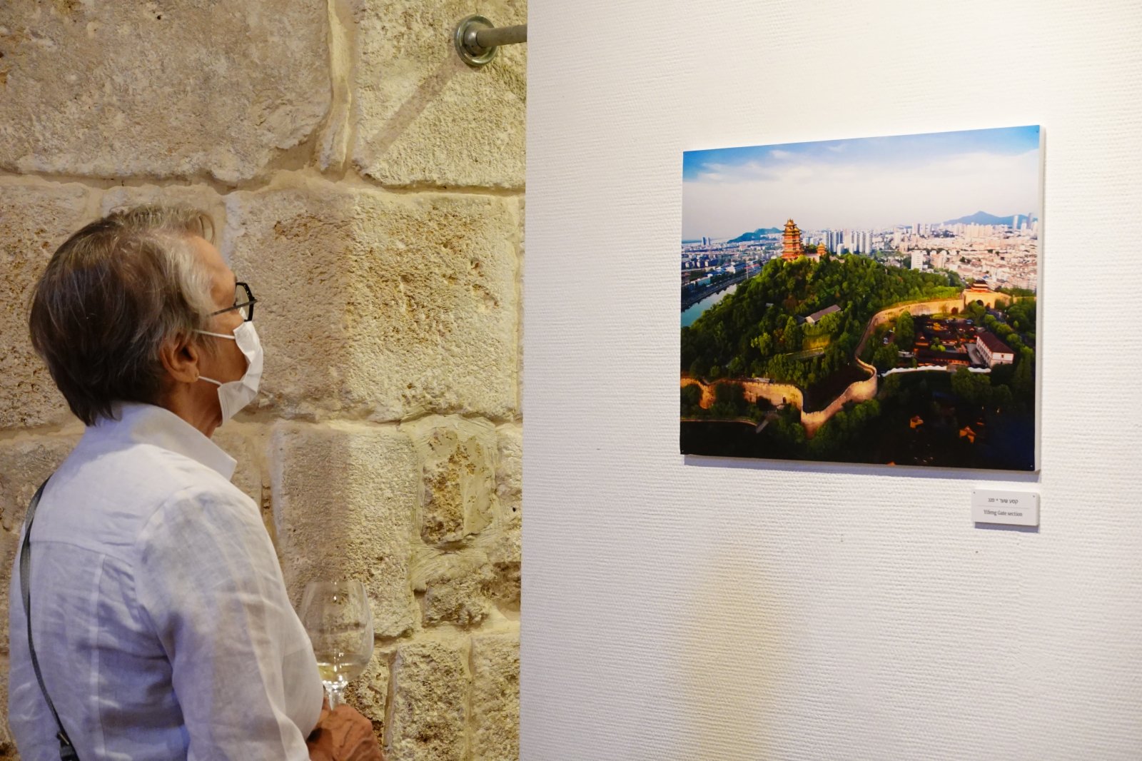 6月13日，一名參觀者在以色列北部海濱古城阿卡舉辦的南京-阿卡城墻圖片展上觀看圖片。新華社