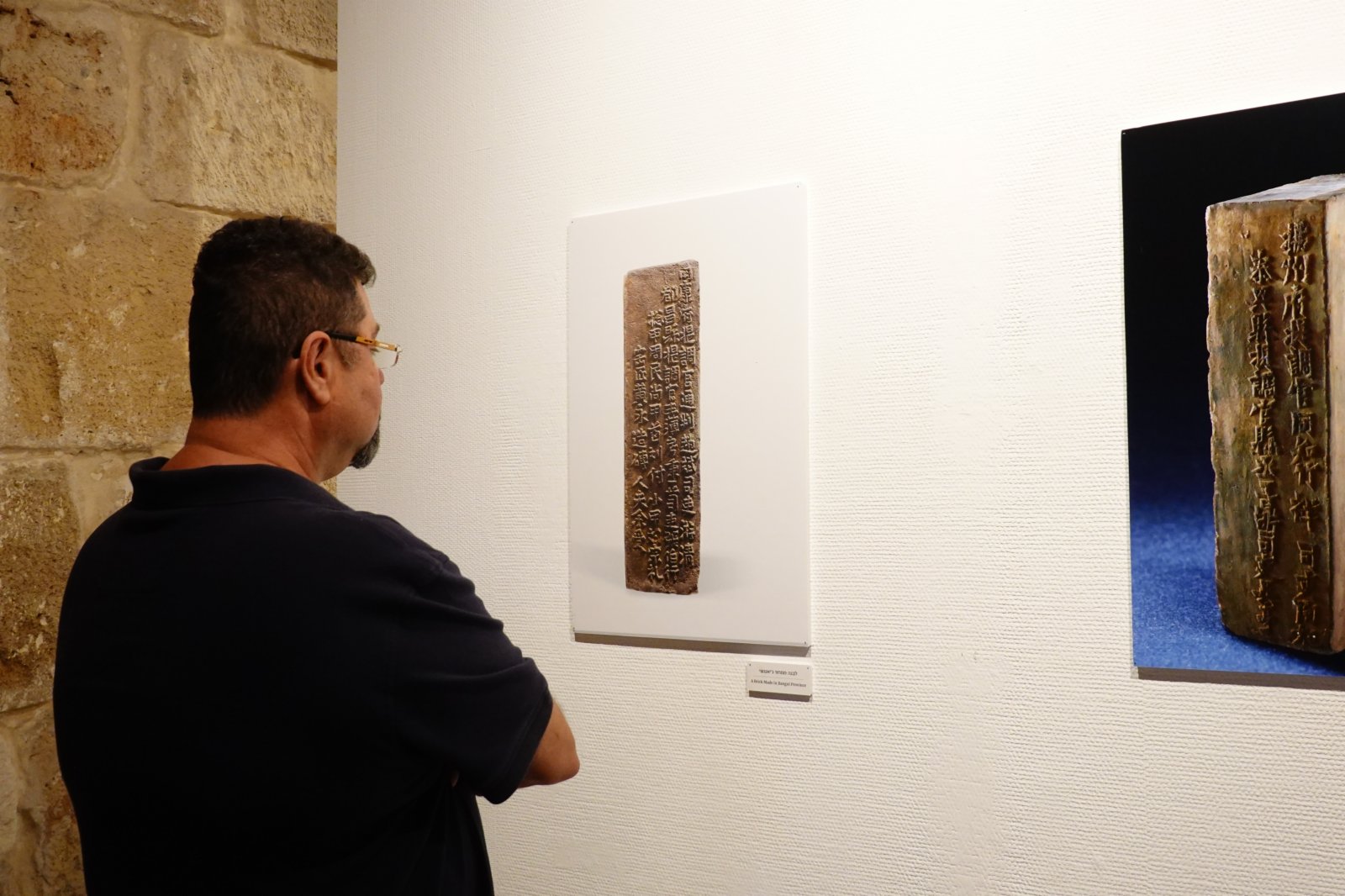 6月13日，一名男子在以色列北部海濱古城阿卡舉辦的南京-阿卡城墻圖片展上參觀。新華社