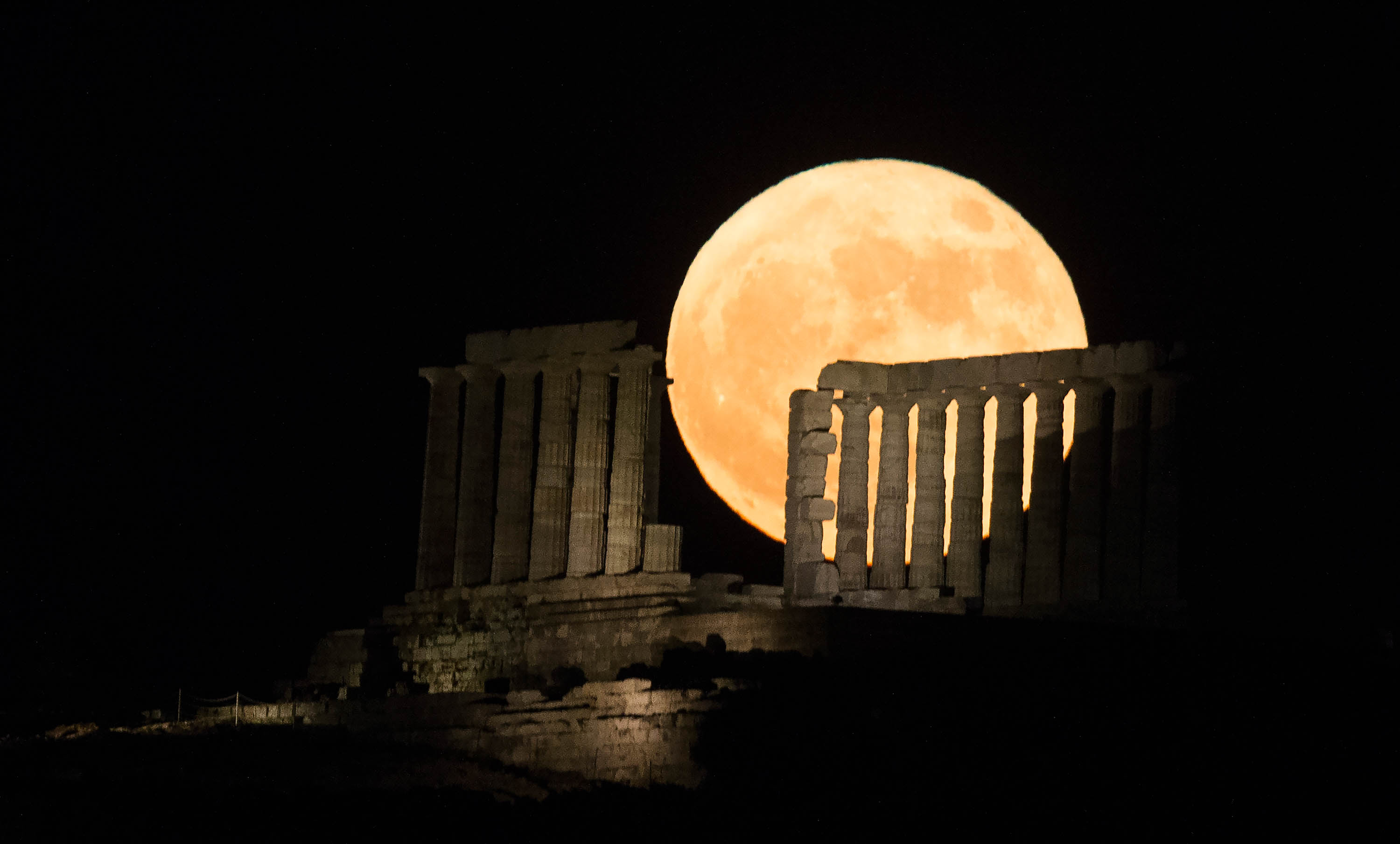 6月14日，「超級月亮」從希臘雅典附近蘇尼翁角的波塞冬神廟後方升起。（新華社）