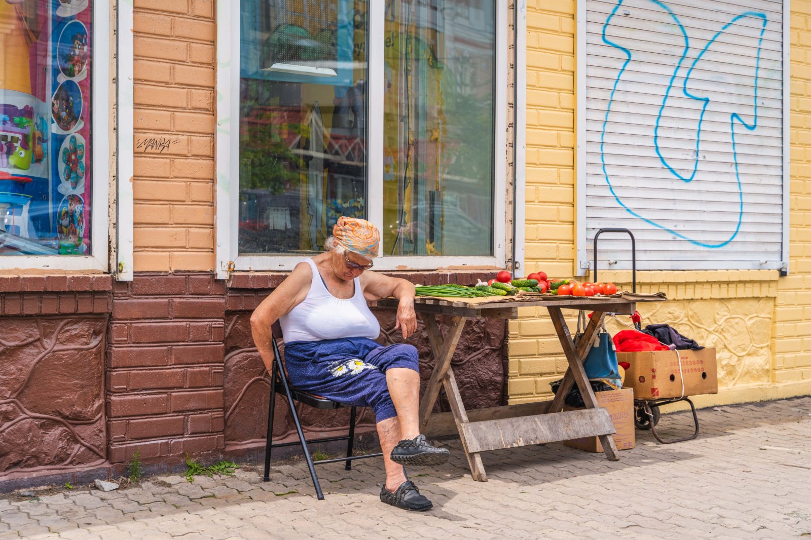 6月18日，俄羅斯符拉迪沃斯托克街頭賣菜的老人在午後的陽光下打盹。（新華社）