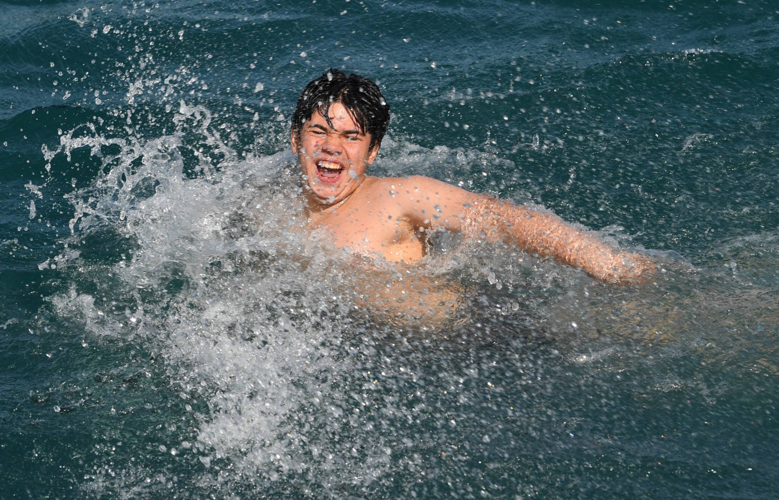一名男孩在土耳其伊斯坦布爾的博斯普魯斯海峽游泳。（新華社）