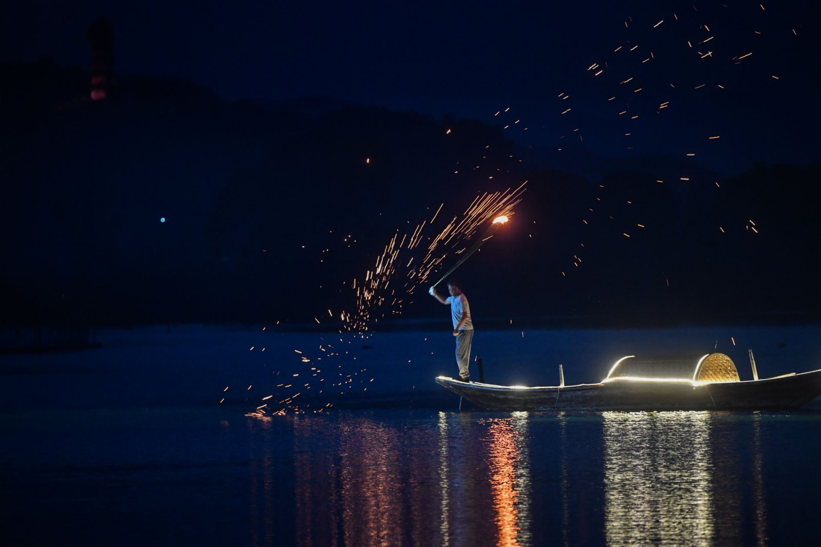 7月3日，三都漁村旁的江面上船隊船燈亮起，工作人員在船頭進行「漁火」煙花表演。（新華社）