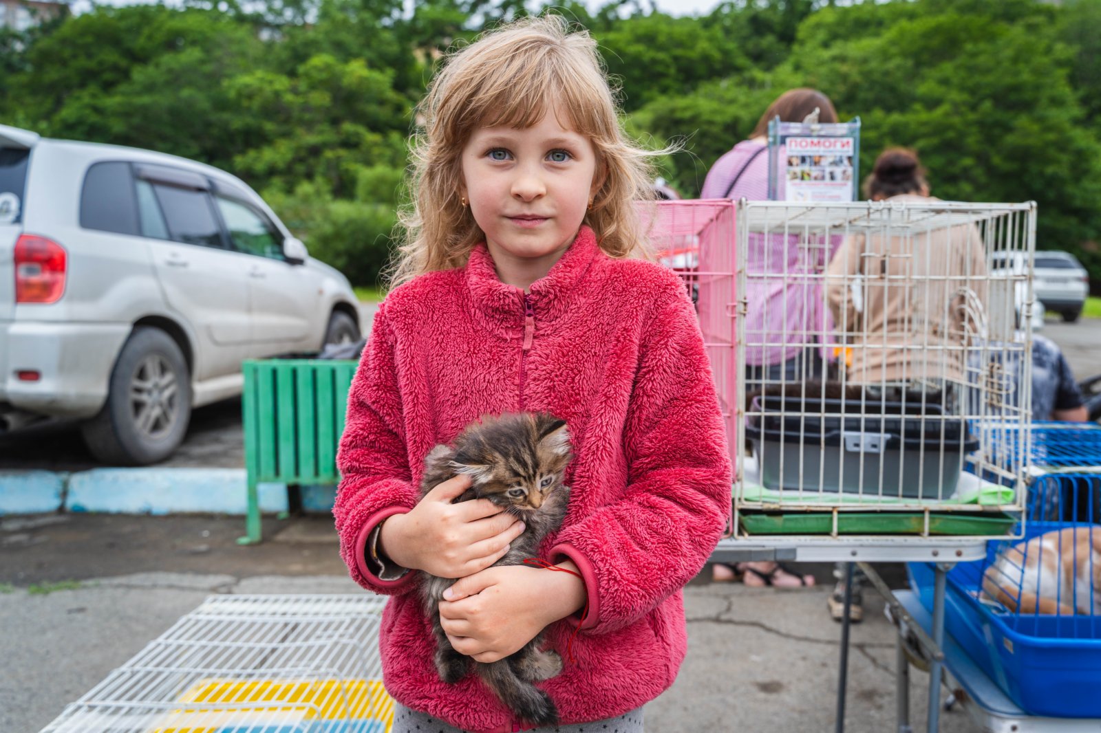 7月23日，在俄羅斯符拉迪沃斯托克市雷鎮公園內，一個女孩抱着一隻流浪貓。（新華社）