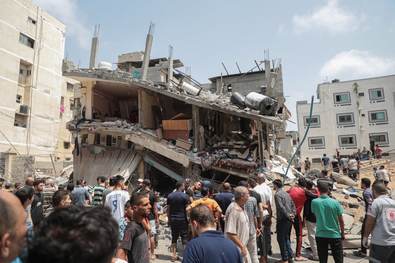 加沙城遭遇空襲後，人們查看損毀的樓房。新華社