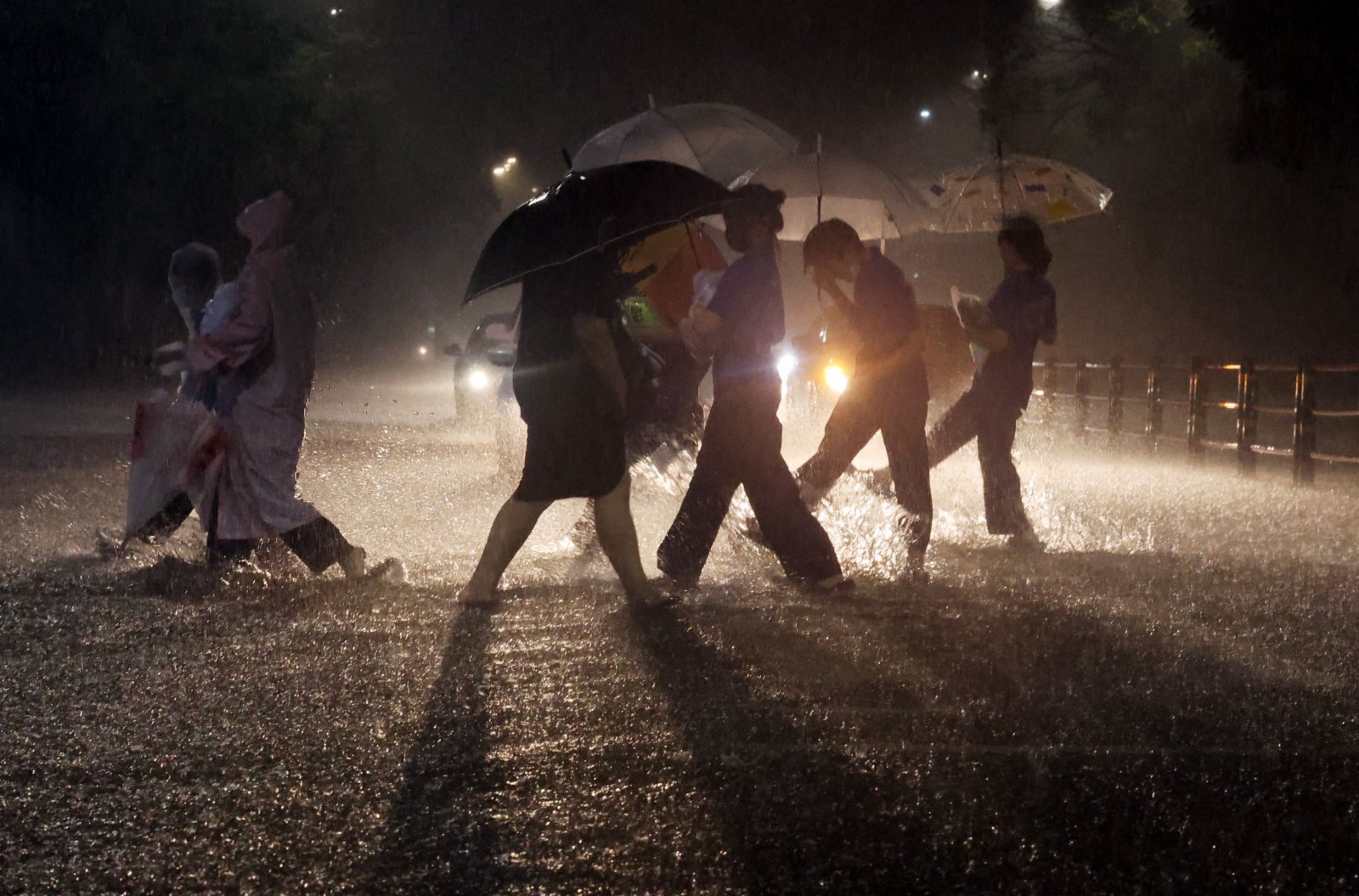圖為首爾江北地區，人們在暴雨中涉水出行。（法新社）