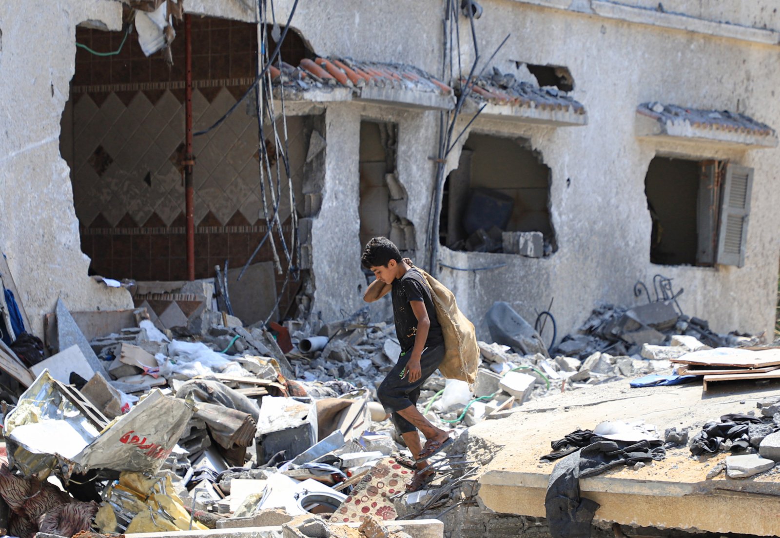 8月9日，在加沙城，一名男孩走在空襲後自家房屋的廢墟上。（新華社）