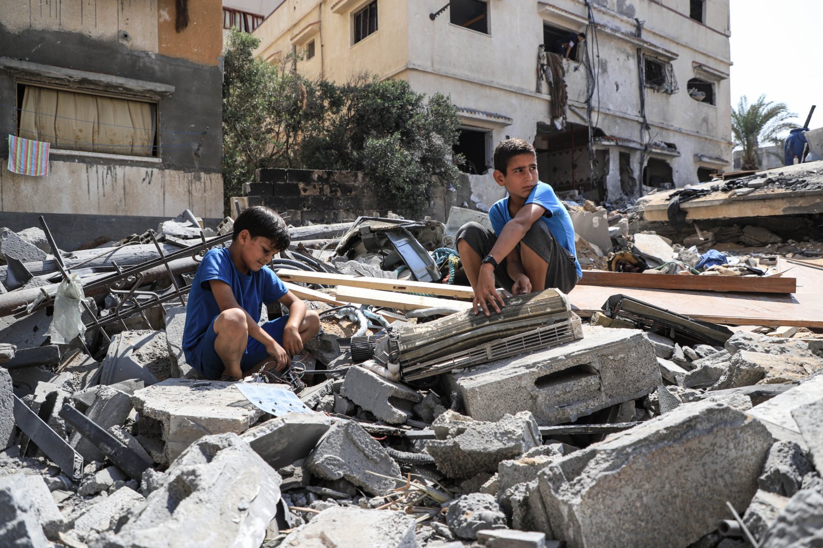 8月9日，在加沙城，兩名男孩坐在空襲後自家房屋的廢墟上。（新華社）
