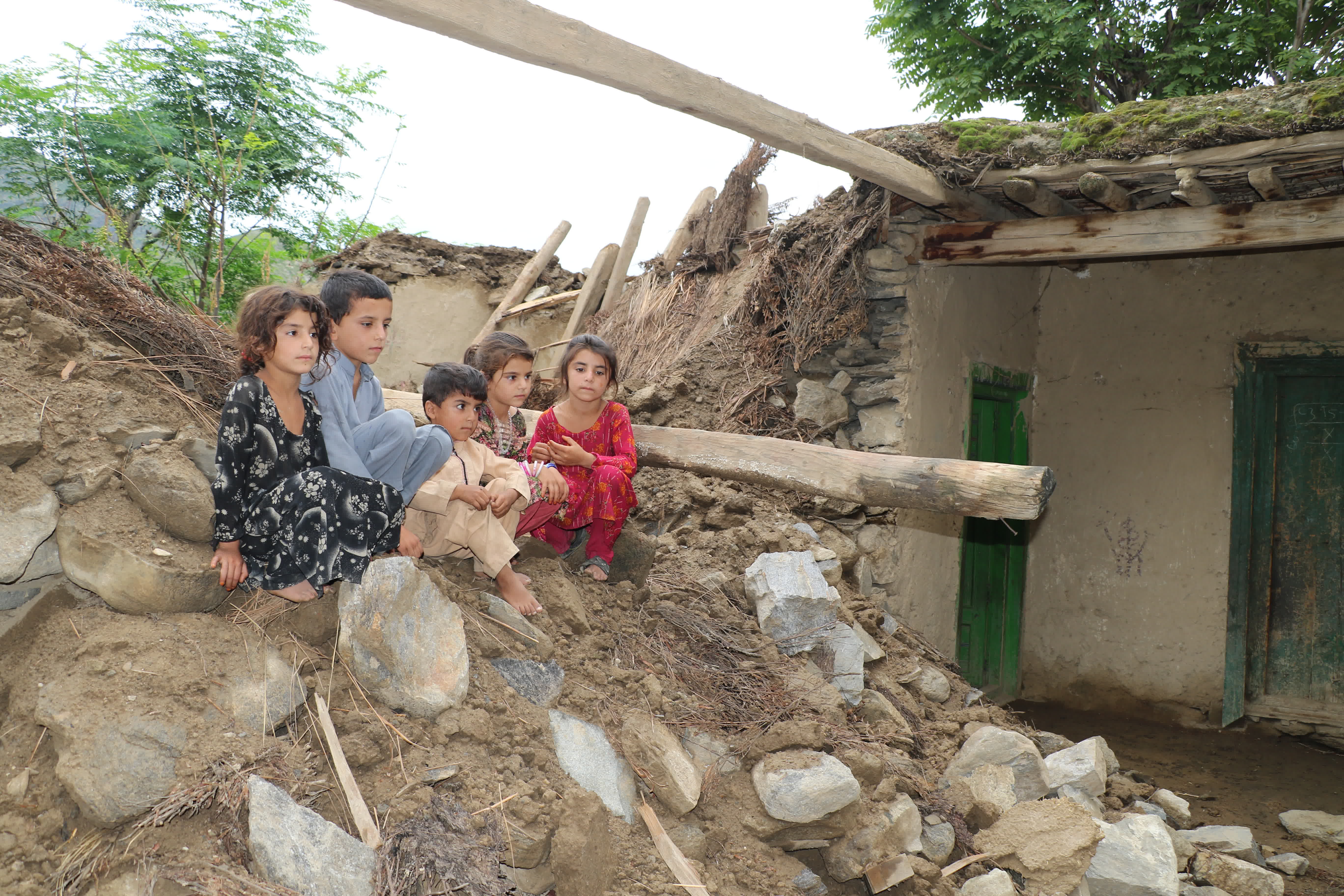 8月18日，孩子們坐在阿富汗努里斯坦省被洪水損毀的房屋廢墟上。（新華社）