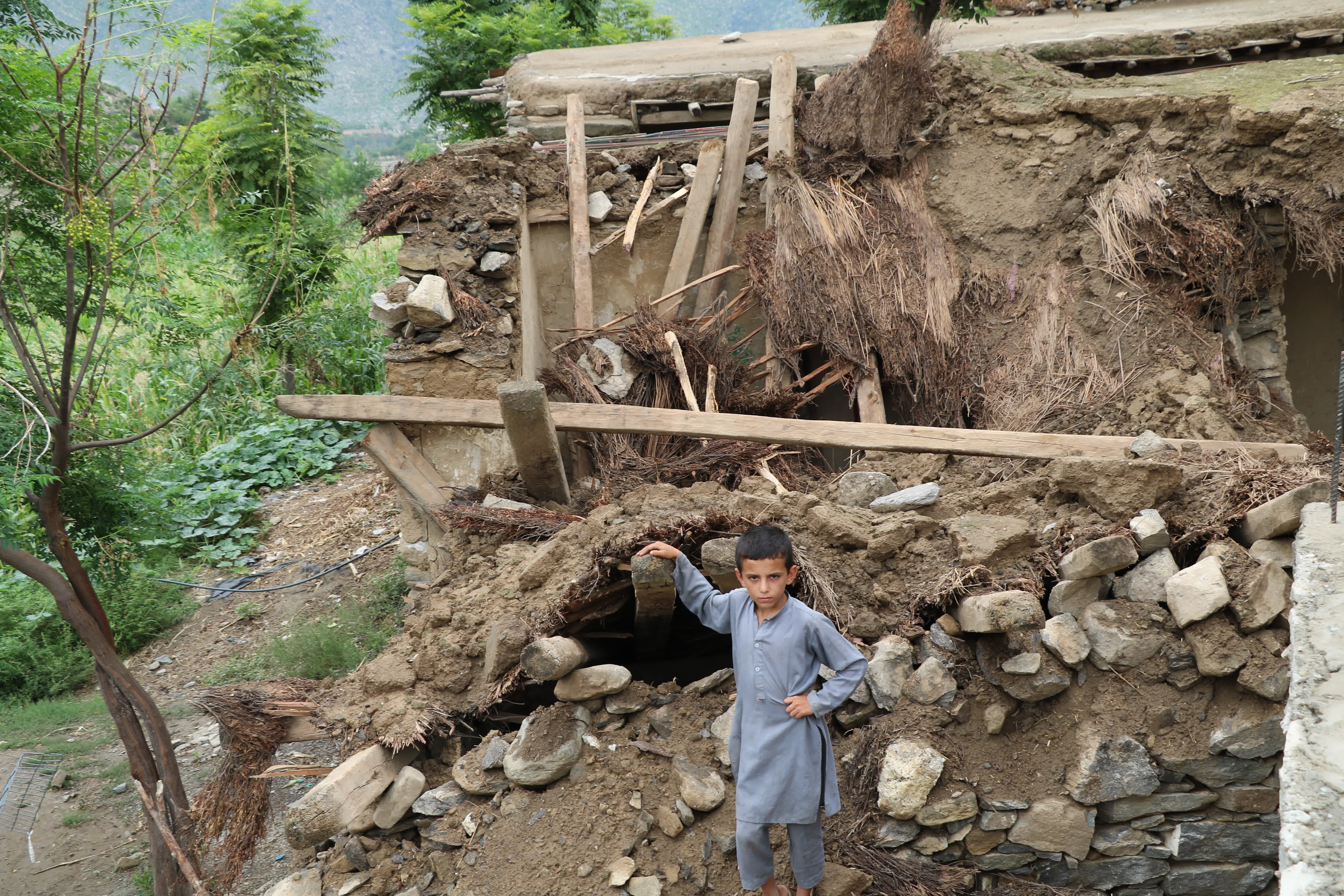 8月18日，一名男孩站在阿富汗努里斯坦省被洪水損毀的房屋旁。（新華社）