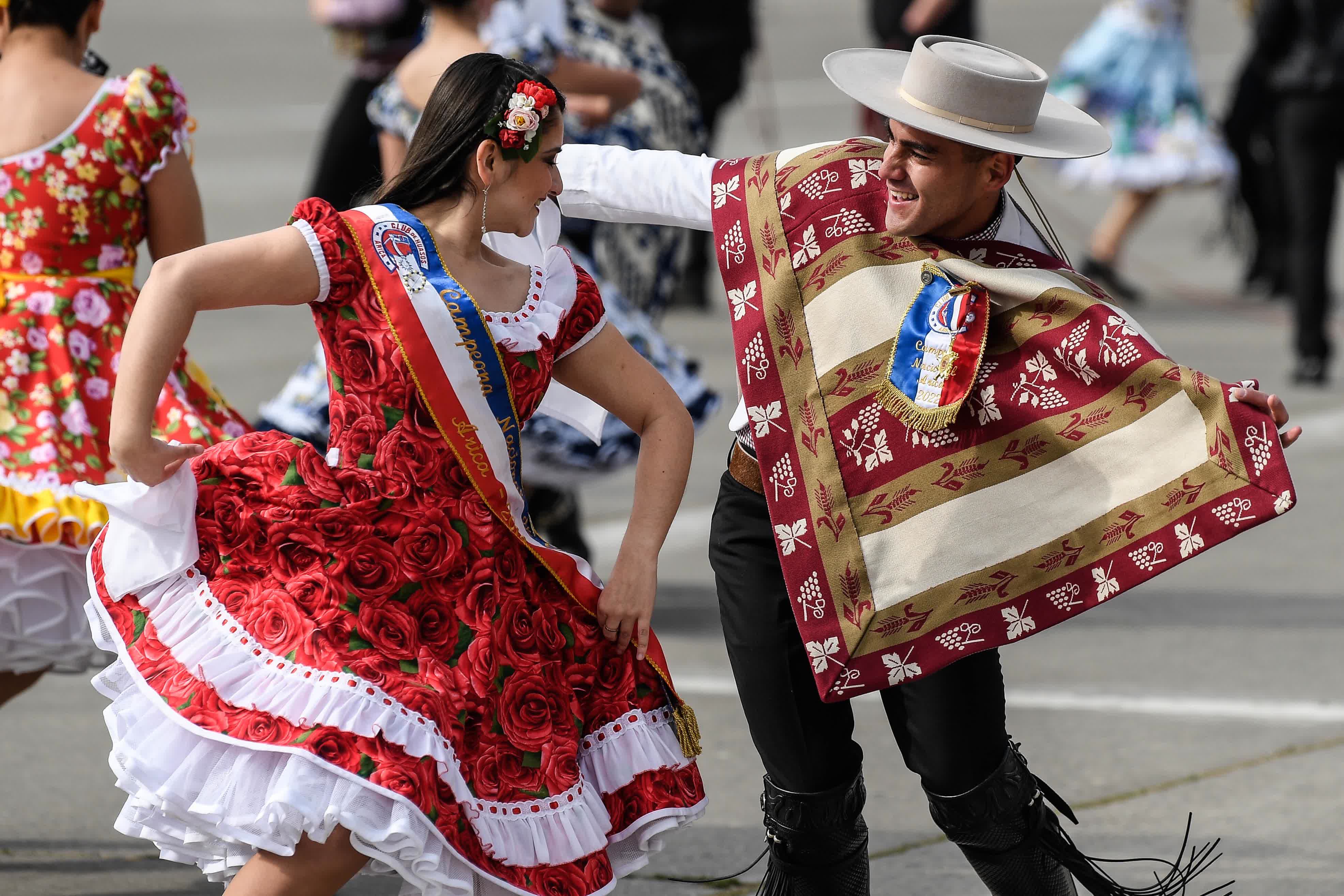 9月19日，在智利首都聖地亞哥，陸軍節閱兵式開始前身穿民族服裝的舞者跳起傳統舞蹈奎卡。（新華社）
