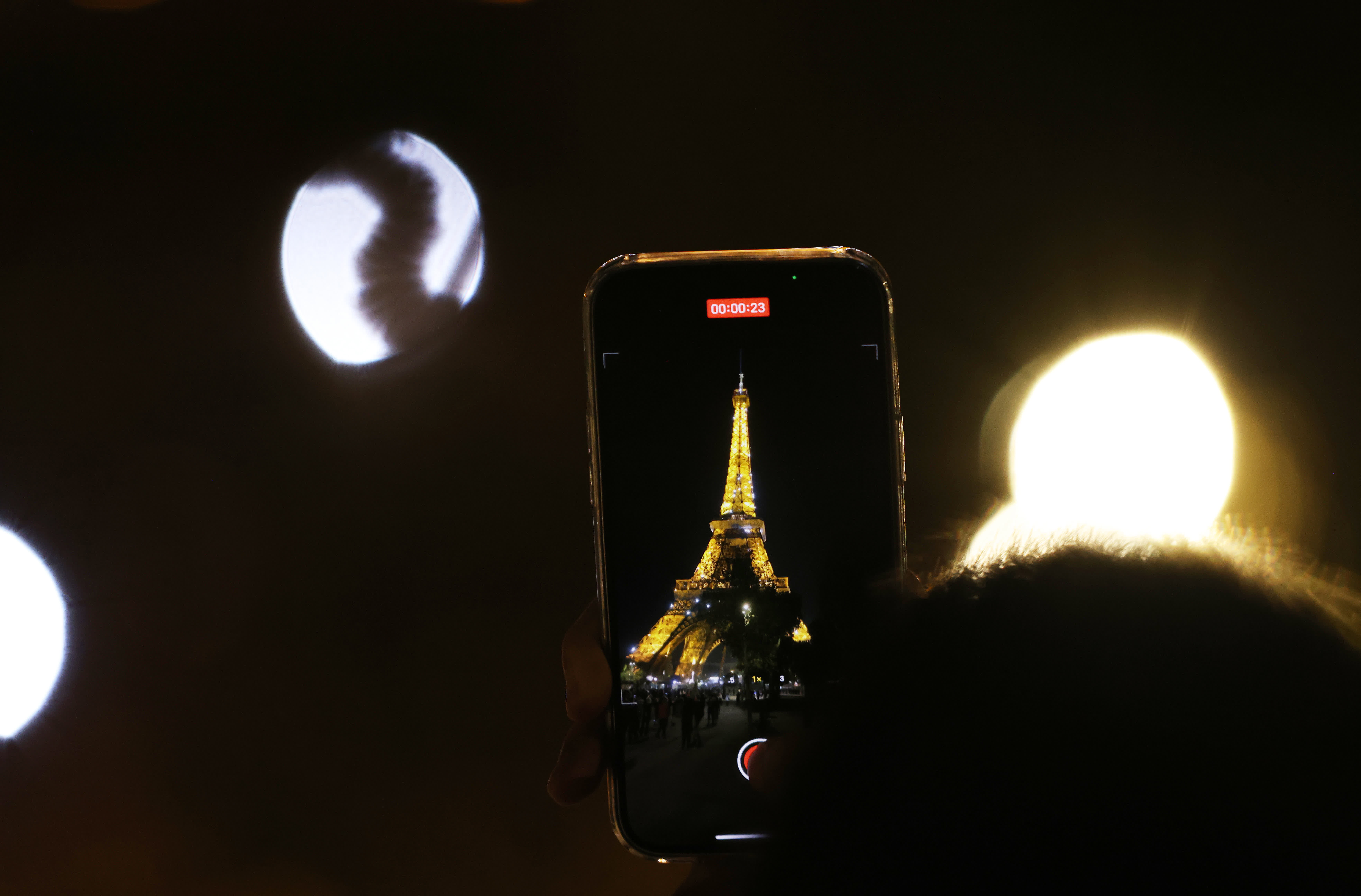 9月22日，一名男子在整點時刻為閃燈的法國巴黎埃菲爾鐵塔錄製視頻。（新華社）