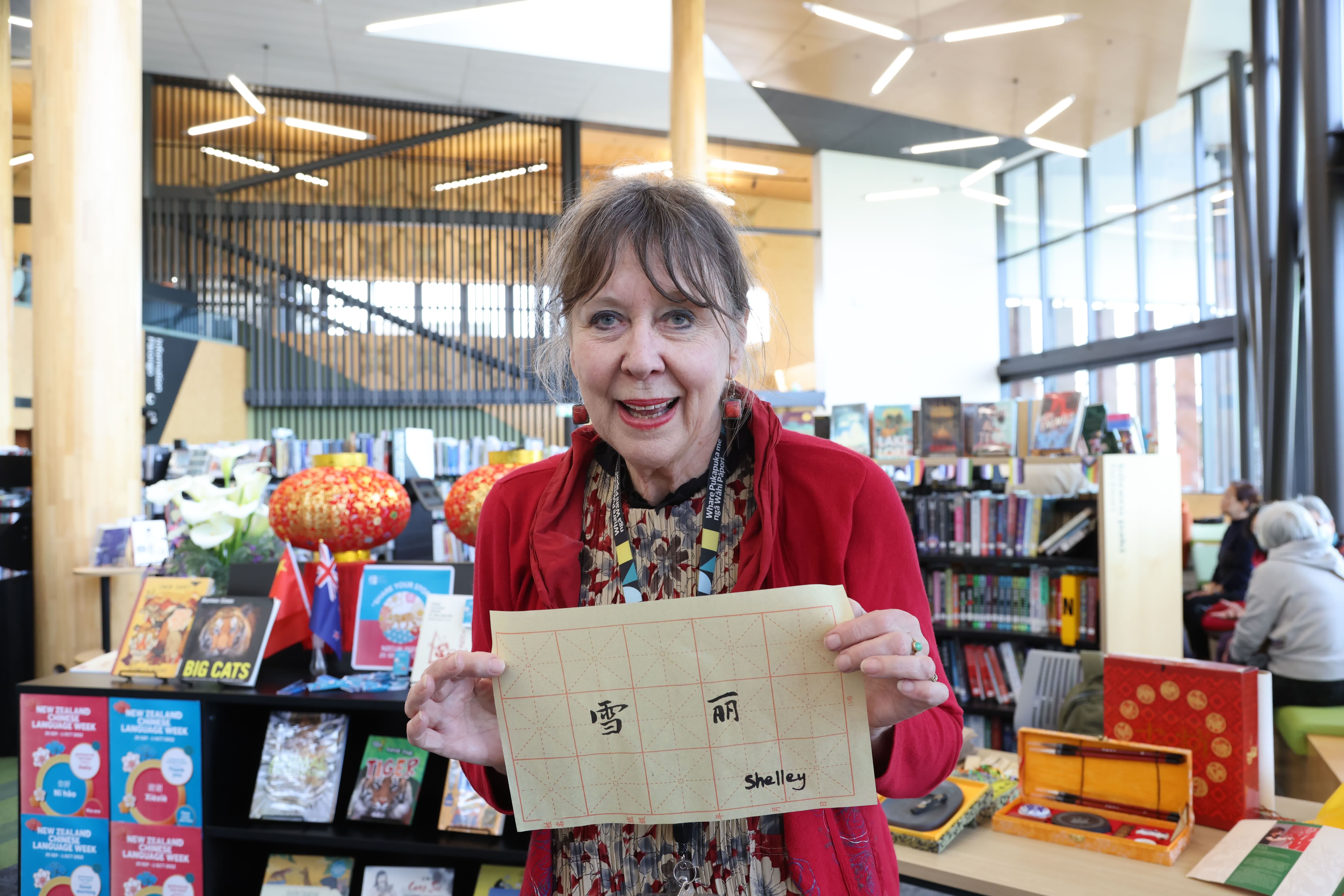 在新西蘭首都惠靈頓一社區圖書館，一名女子展示中國書法老師為她書寫的中文名字。（新華社）