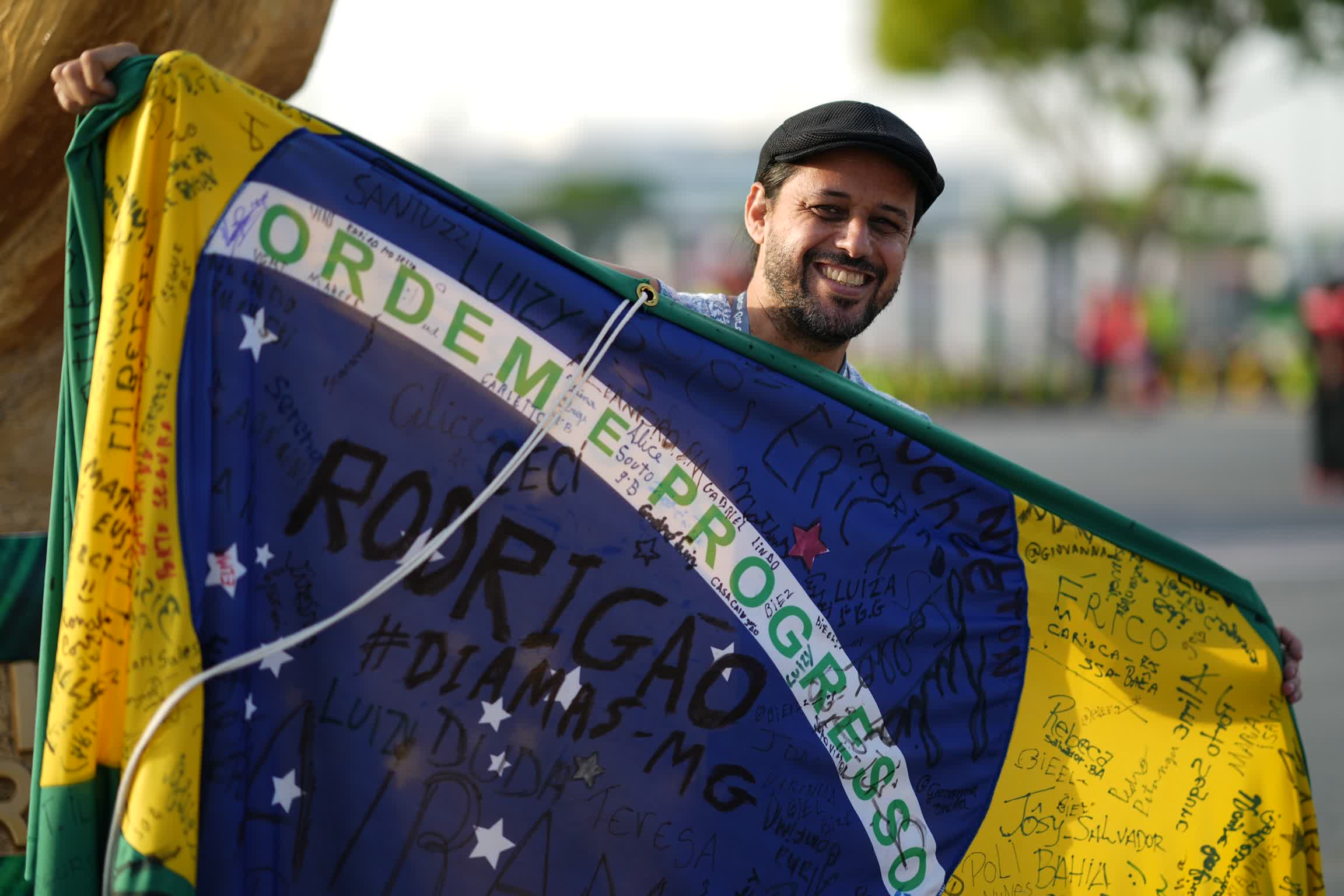 來自巴西的Anderson，在哈里發國際體育場外，展示簽滿其友人名字的巴西國旗。（中新社）