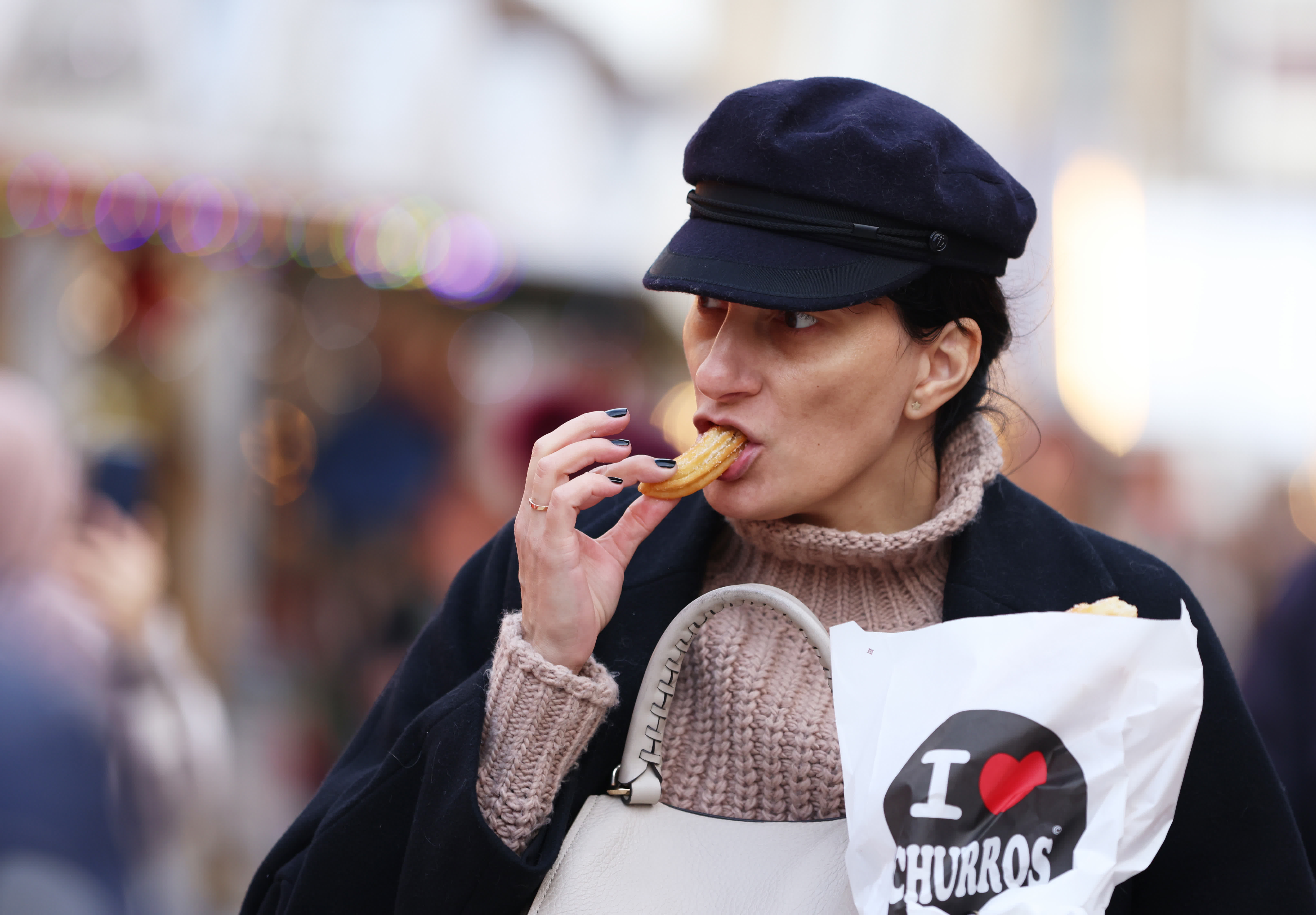 11月24日，一名女子在法國巴黎杜伊勒里花園的聖誕市場享受傳統美食——西班牙油條。（新華社）