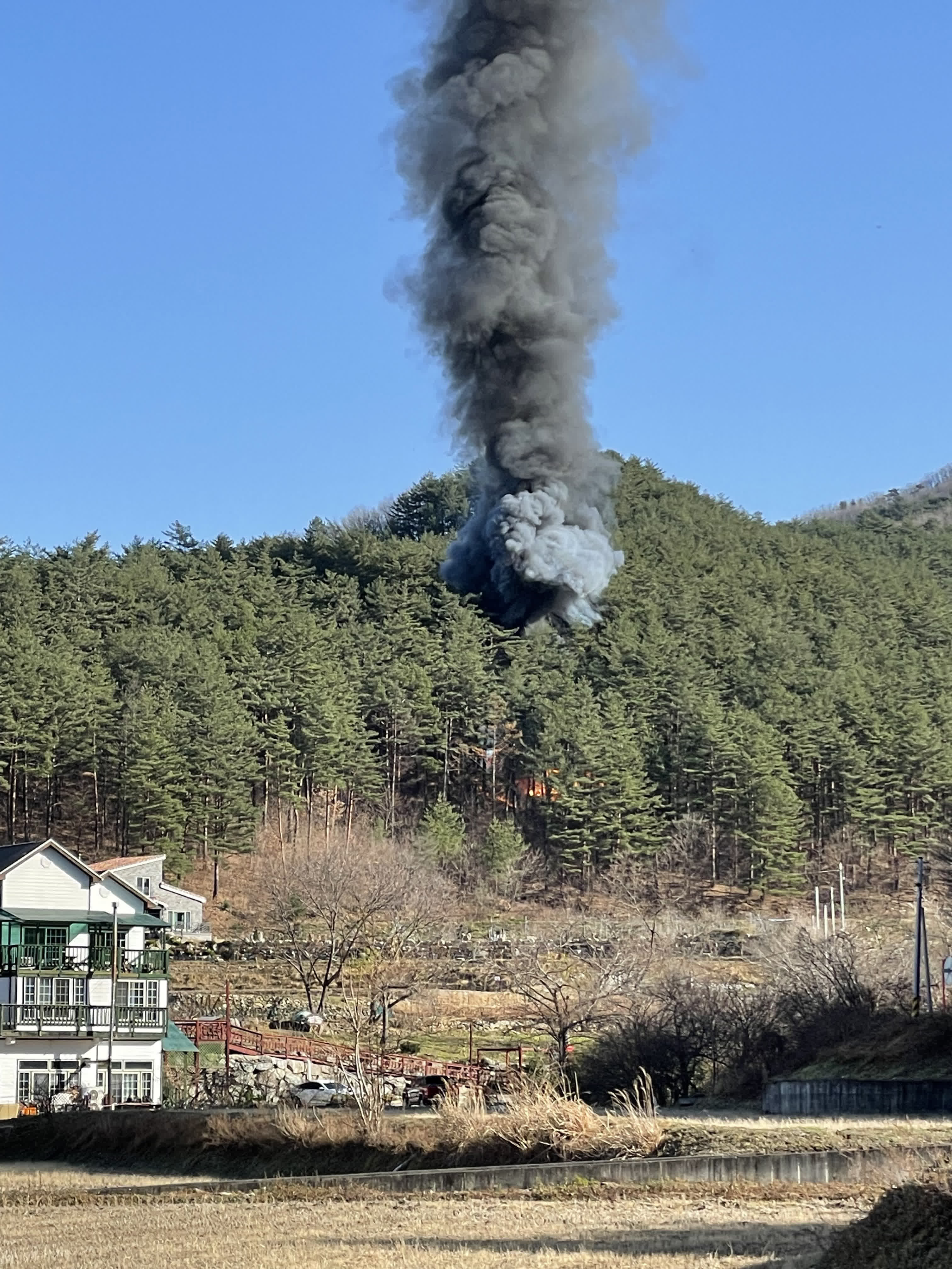 11月27日，在韓國江原道襄陽郡，直升機墜毀現場冒起濃煙。（新華社）