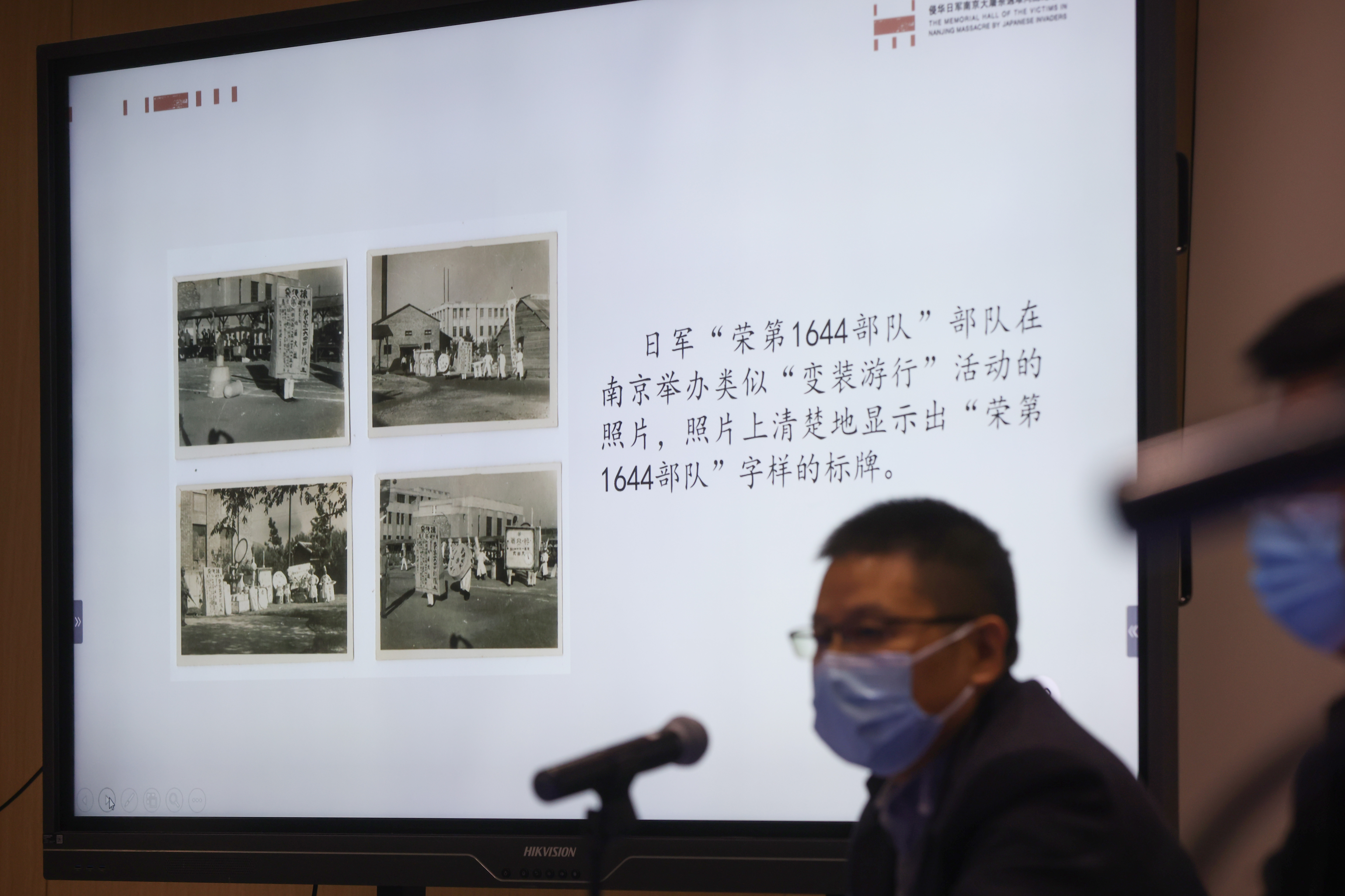 工作人員介紹侵華日軍「榮第1644部隊」在南京舉辦類似「變裝遊行」活動的照片，照片上清楚地顯示出「榮第1644部隊」字樣的標牌。（中新社）