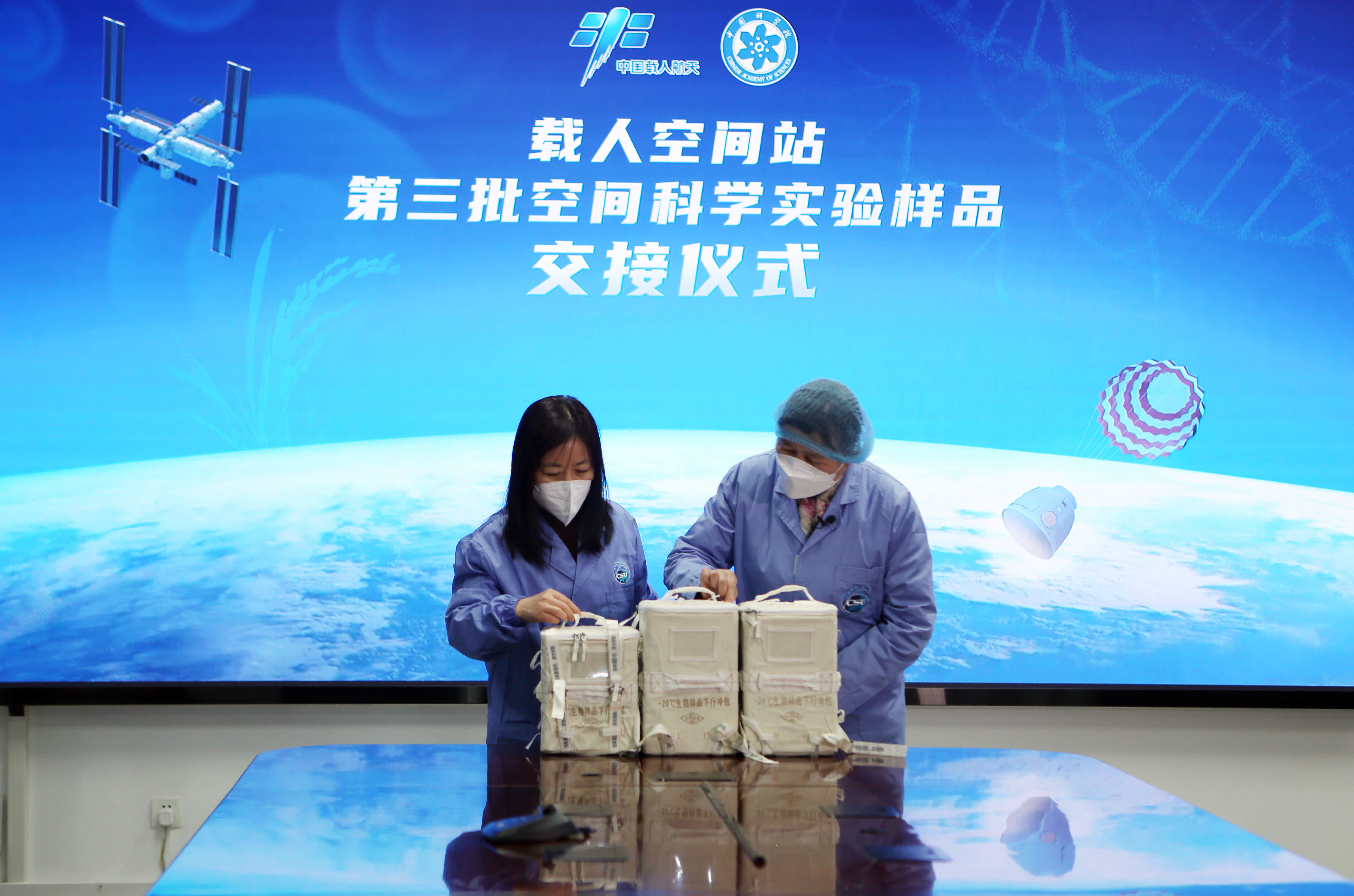 12月5日，在中國科學院空間應用中心，空間應用中心科研人員（左）向分子植物卓越中心科研人員交接樣品。（新華社）