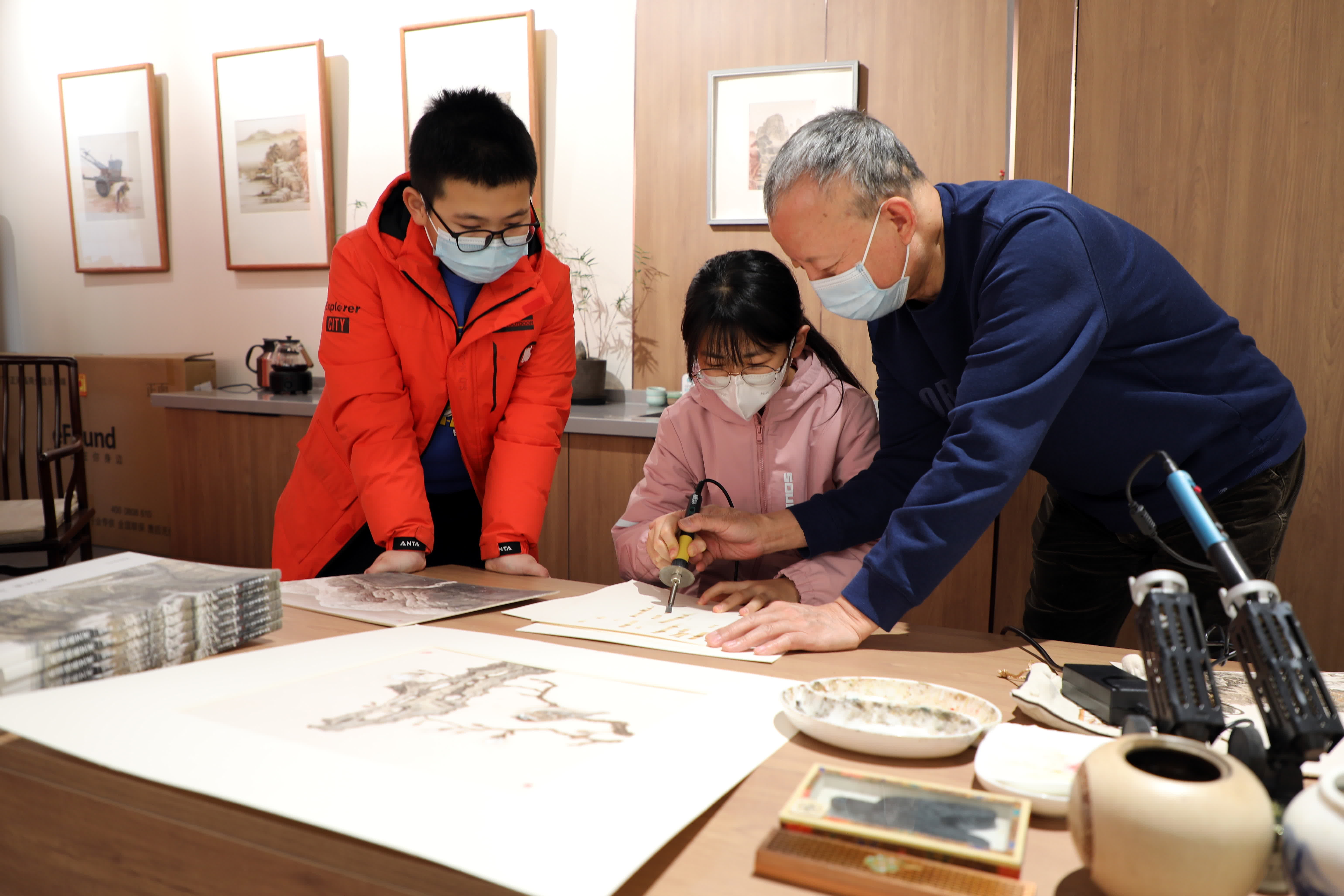 1月9日，在石家莊市灣里廟步行街郝友友民間文藝家工作室，烙畫藝術家郝友友（右）指導孩子們學習烙畫技藝。（新華社）