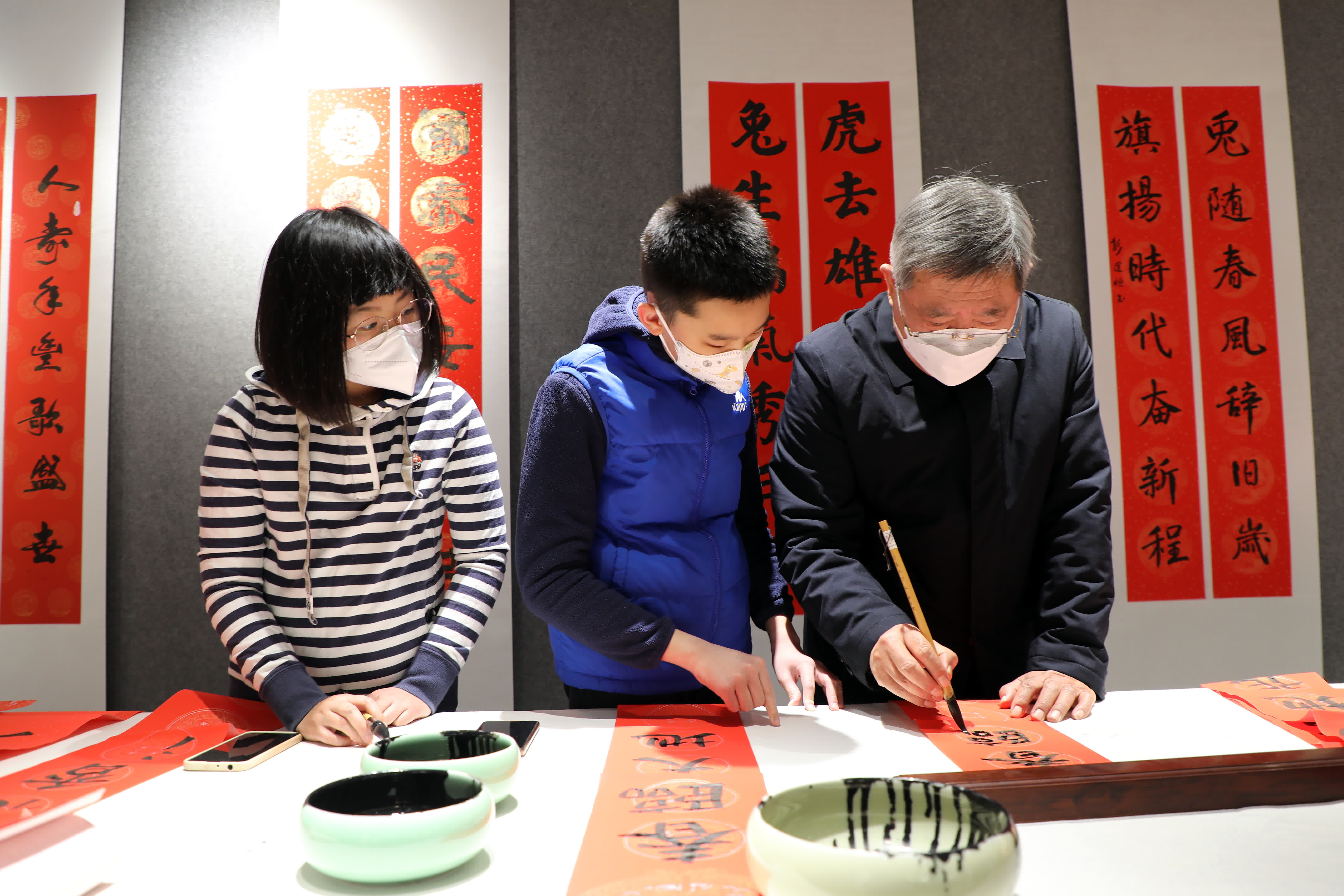1月9日，在石家莊市劉金凱書法家工作室，書法家劉金凱（右）指導書法小學員寫春聯。（新華社）