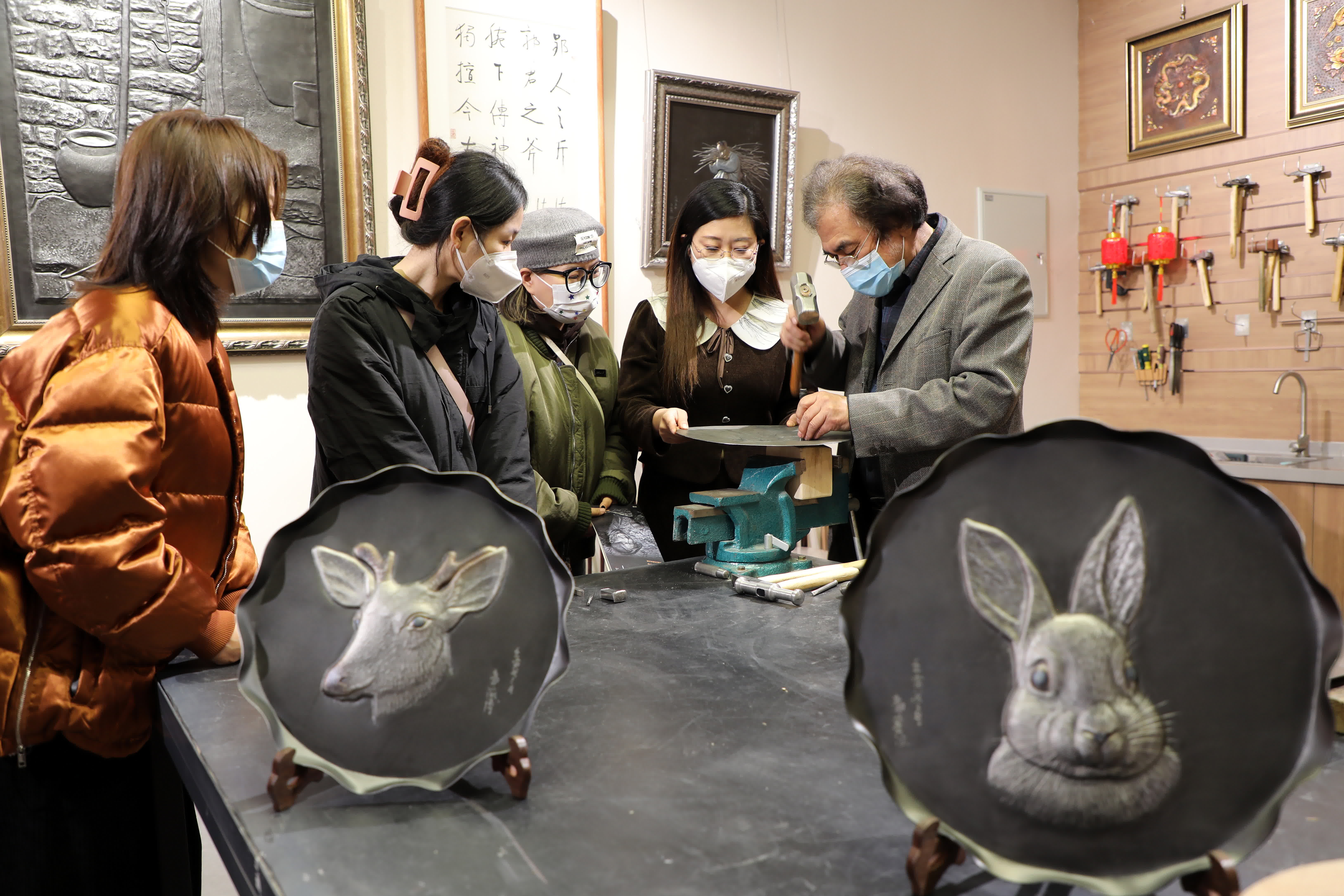 1月9日，在石家莊市灣里廟步行街郭海博民間文藝家工作室，鐵板浮雕藝術家郭海博（右一）在向觀眾介紹鐵板浮雕技藝。（新華社）