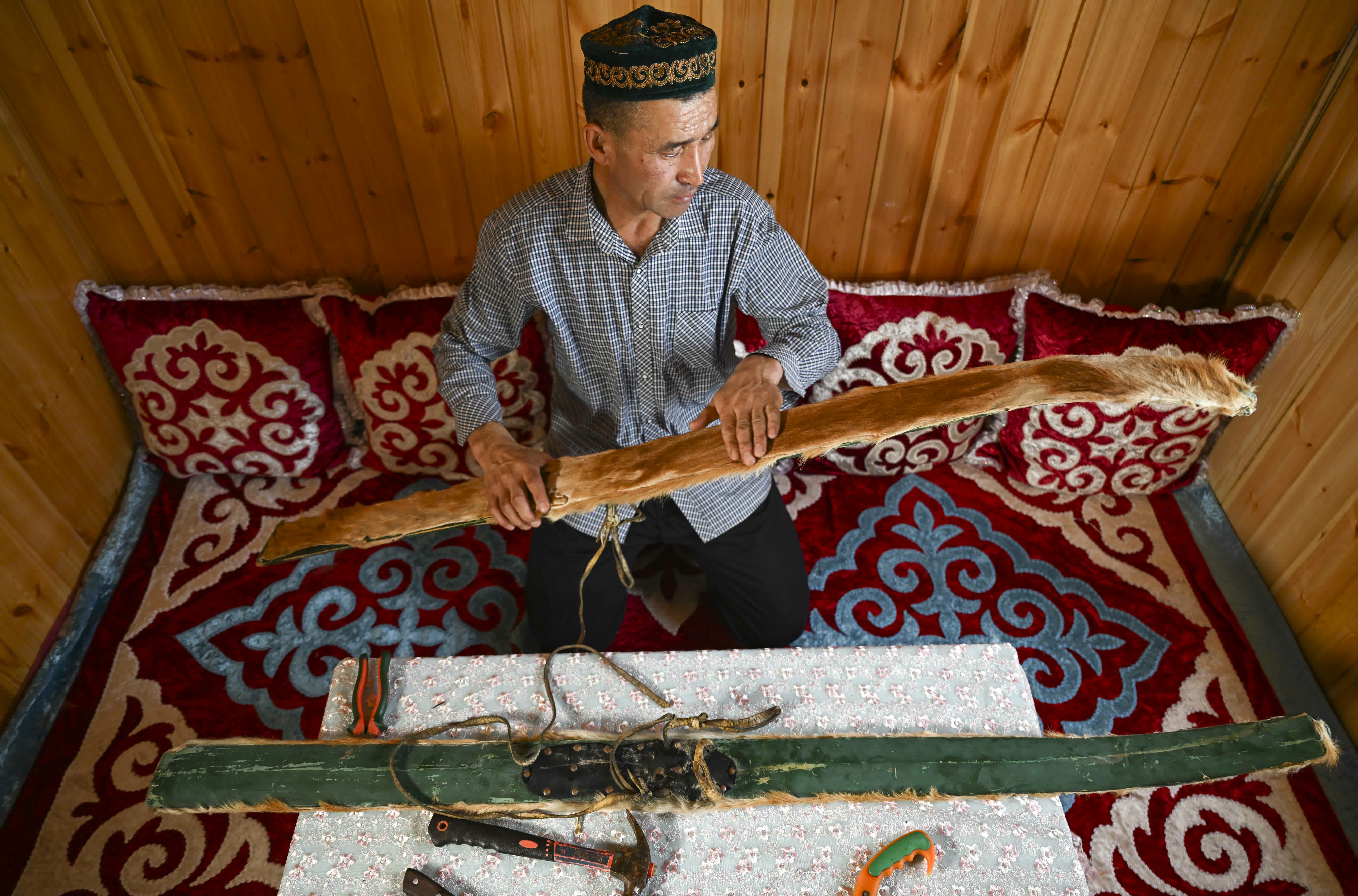 新疆阿勒泰地區富蘊縣可可托海鎮牧民赤合斯·阿斯沙汗在家中展示古老毛皮滑雪板（2022年12月22日攝）。古老毛皮滑雪板已是阿勒泰地區冰雪文旅名片。（新華社）