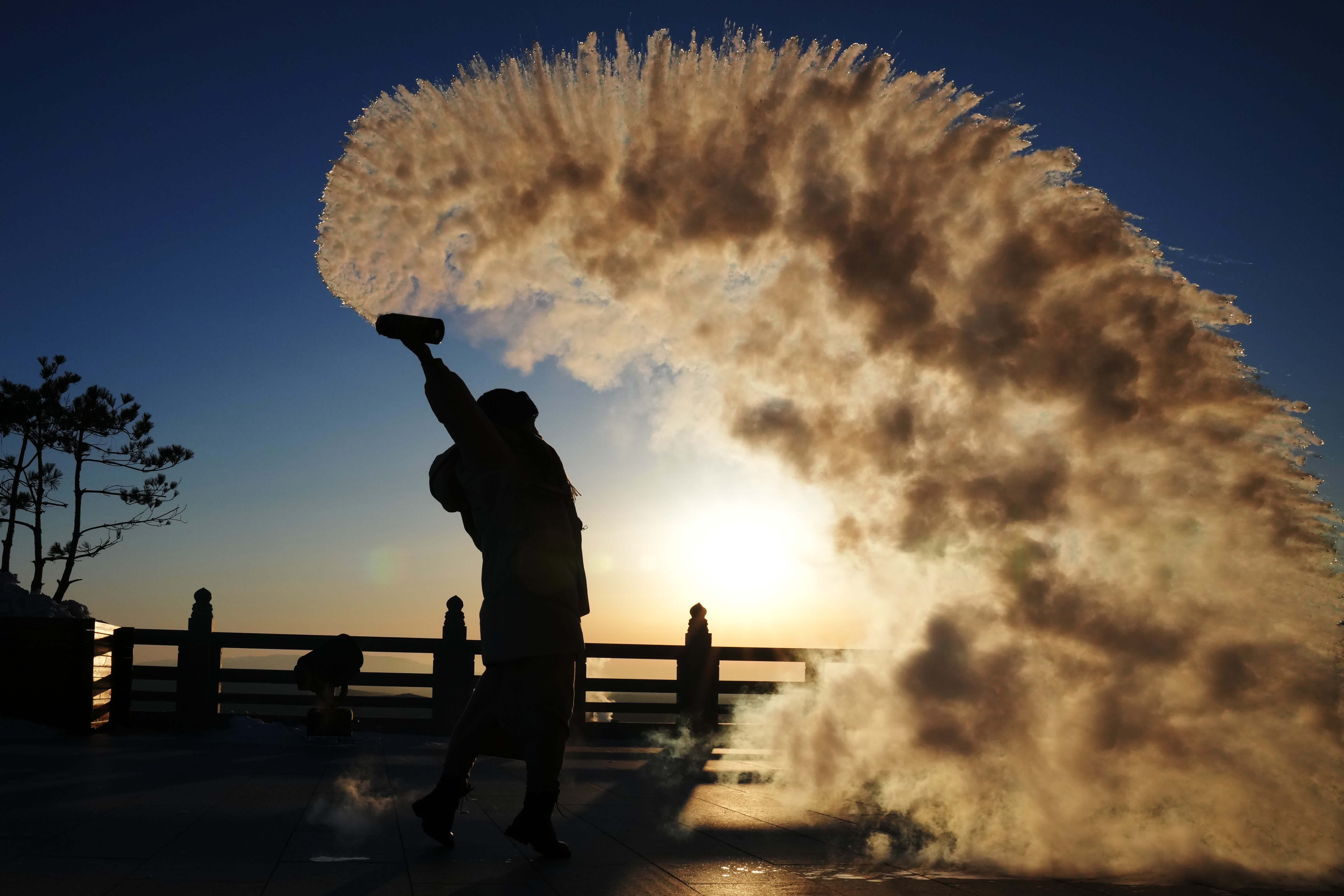 1月14日，在撫遠市東極閣，遊客在日出時玩「潑水成煙」。（新華社）