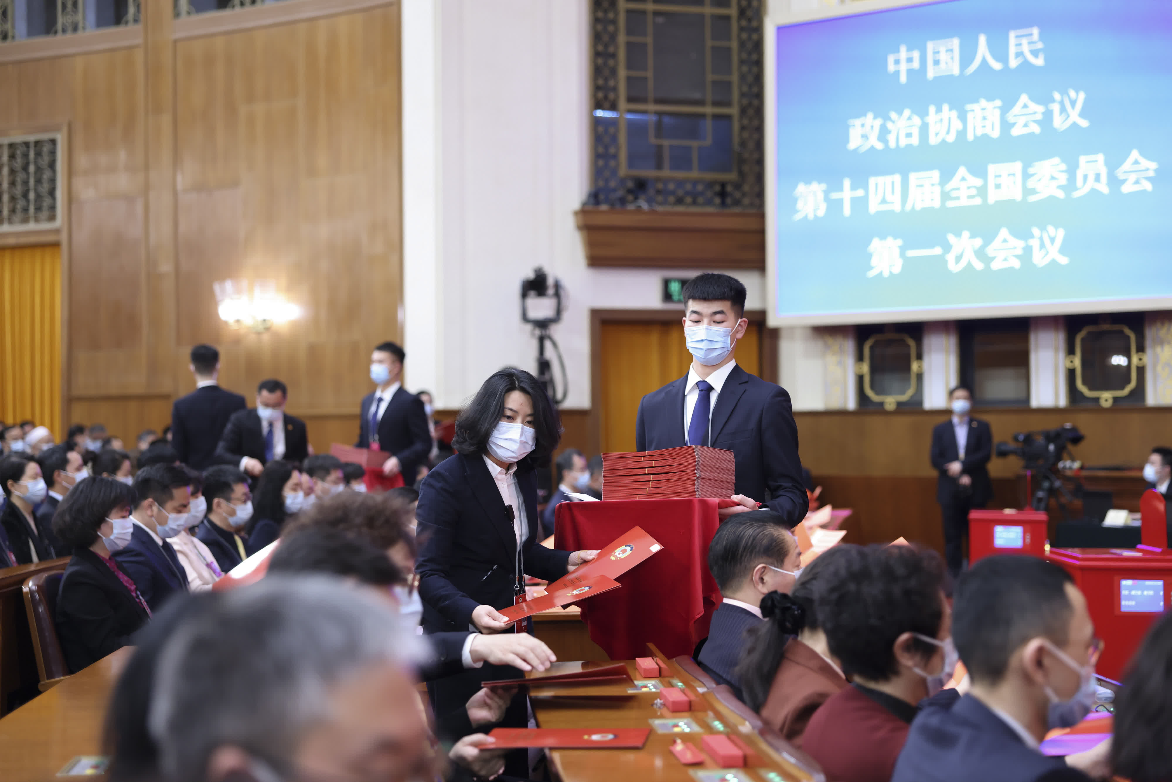 3月10日，全國政協十四屆一次會議在北京人民大會堂舉行第三次全體會議。這是工作人員發放選票。（新華社）
