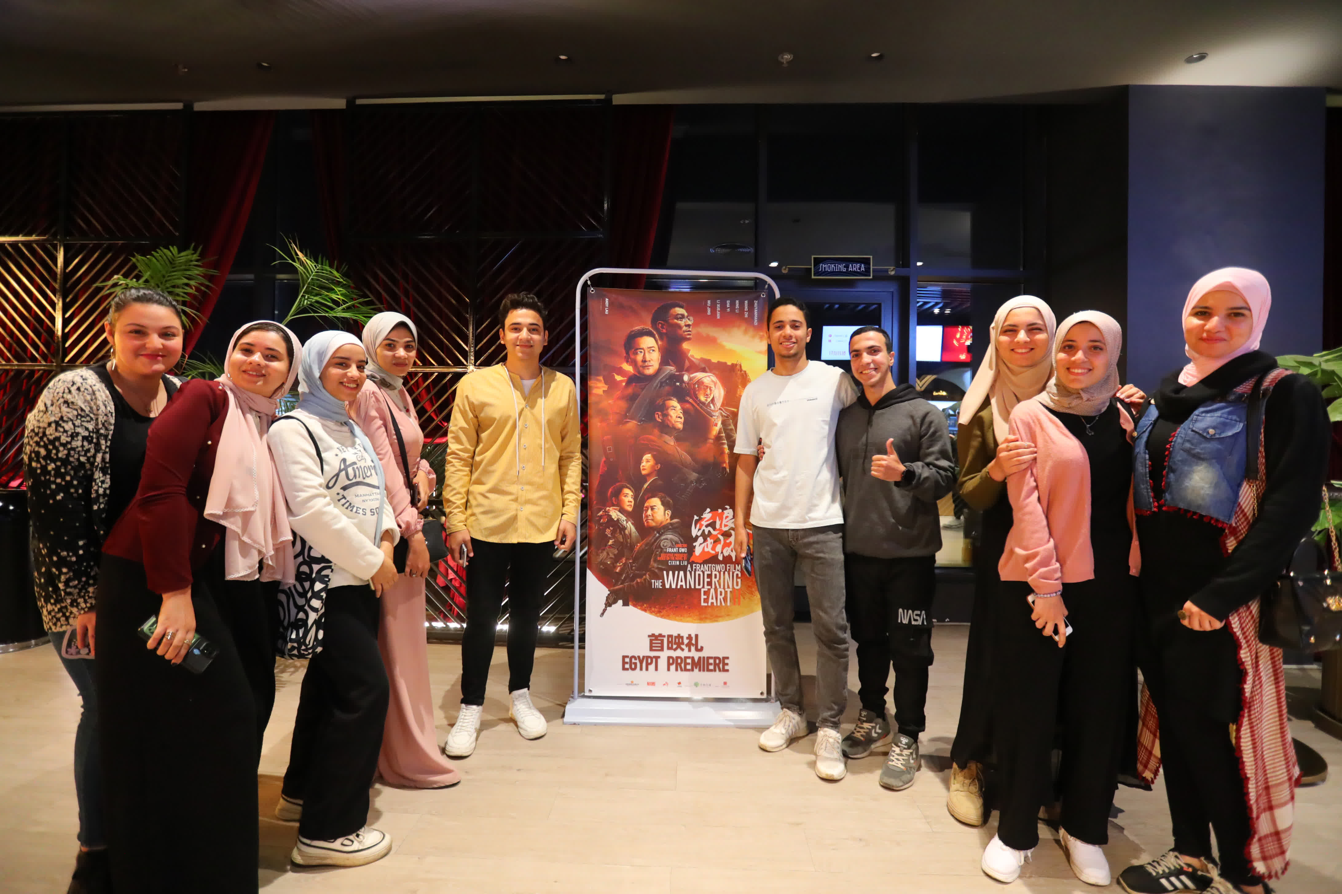 3月11日，人們在埃及吉薩一家電影院與電影《流浪地球2》的海報合影。（新華社）