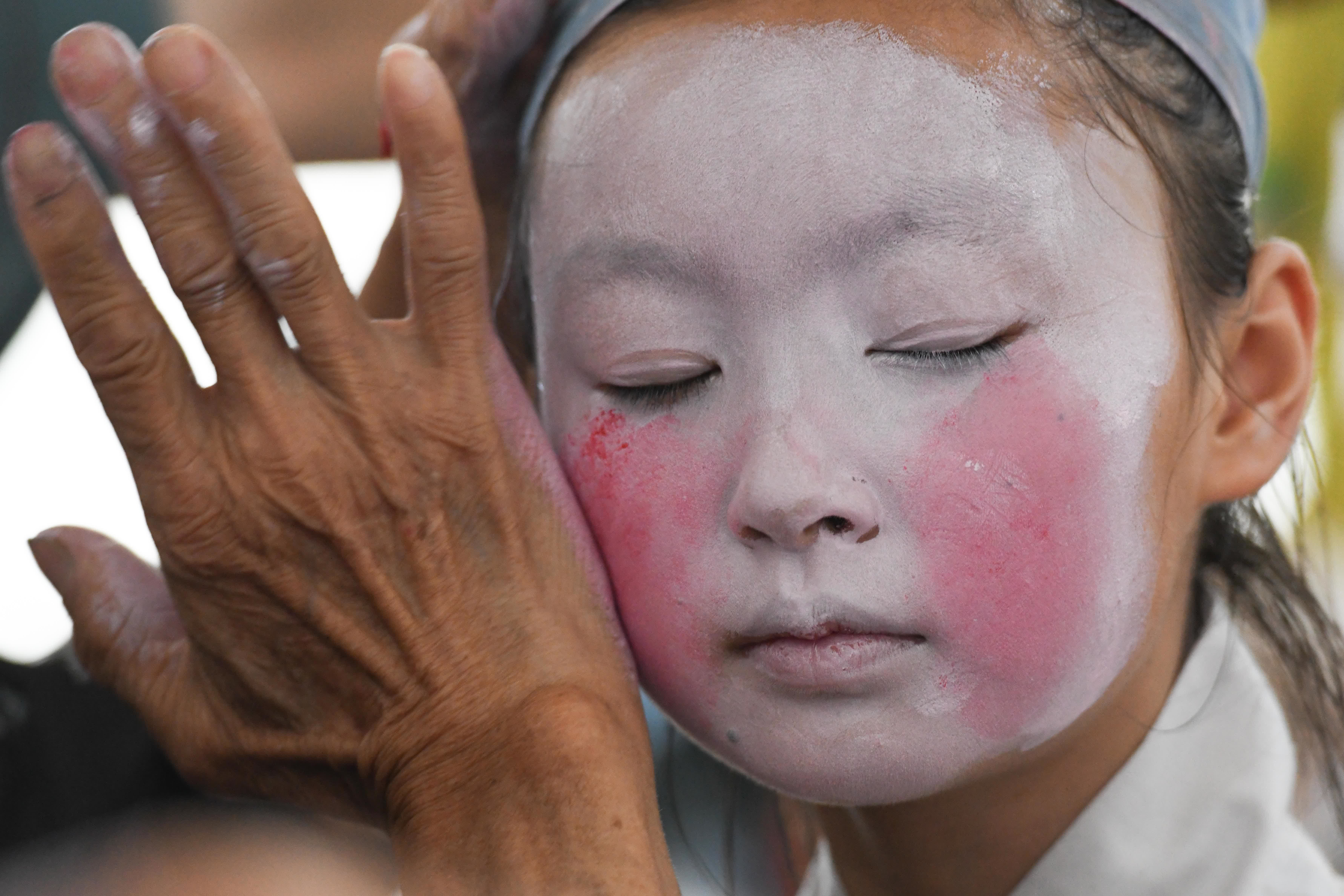5月30日，民間老藝人在給伏嶺鎮中心小學「徽劇童子班」的學生化妝。（新華社）