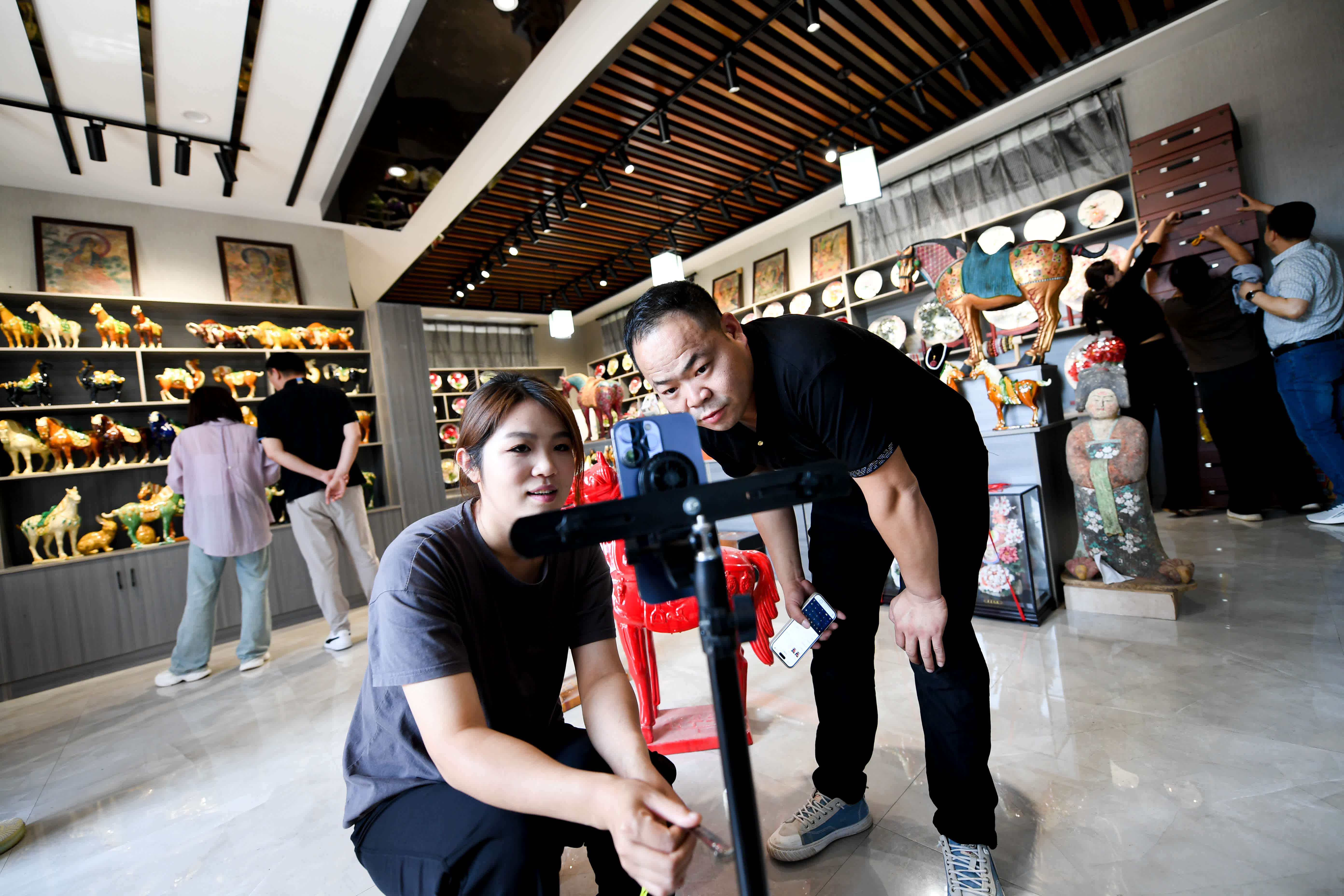 6月6日，工作人員在南石山村的唐三彩商鋪內通過手機直播銷售唐三彩。（新華社）