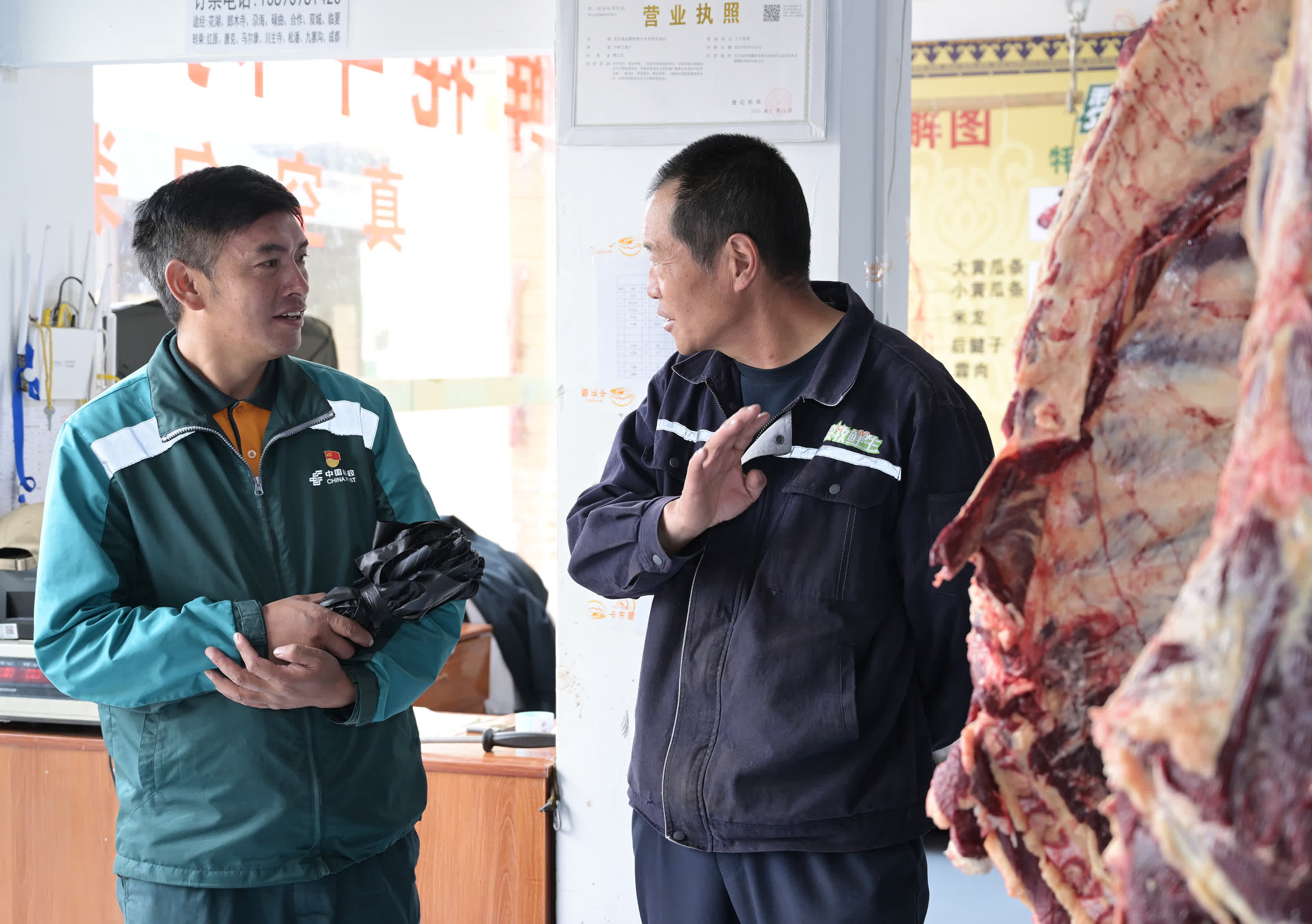 哈弄奪機（左）在該縣一家生鮮肉類銷售店向店長了解情況。（新華社）