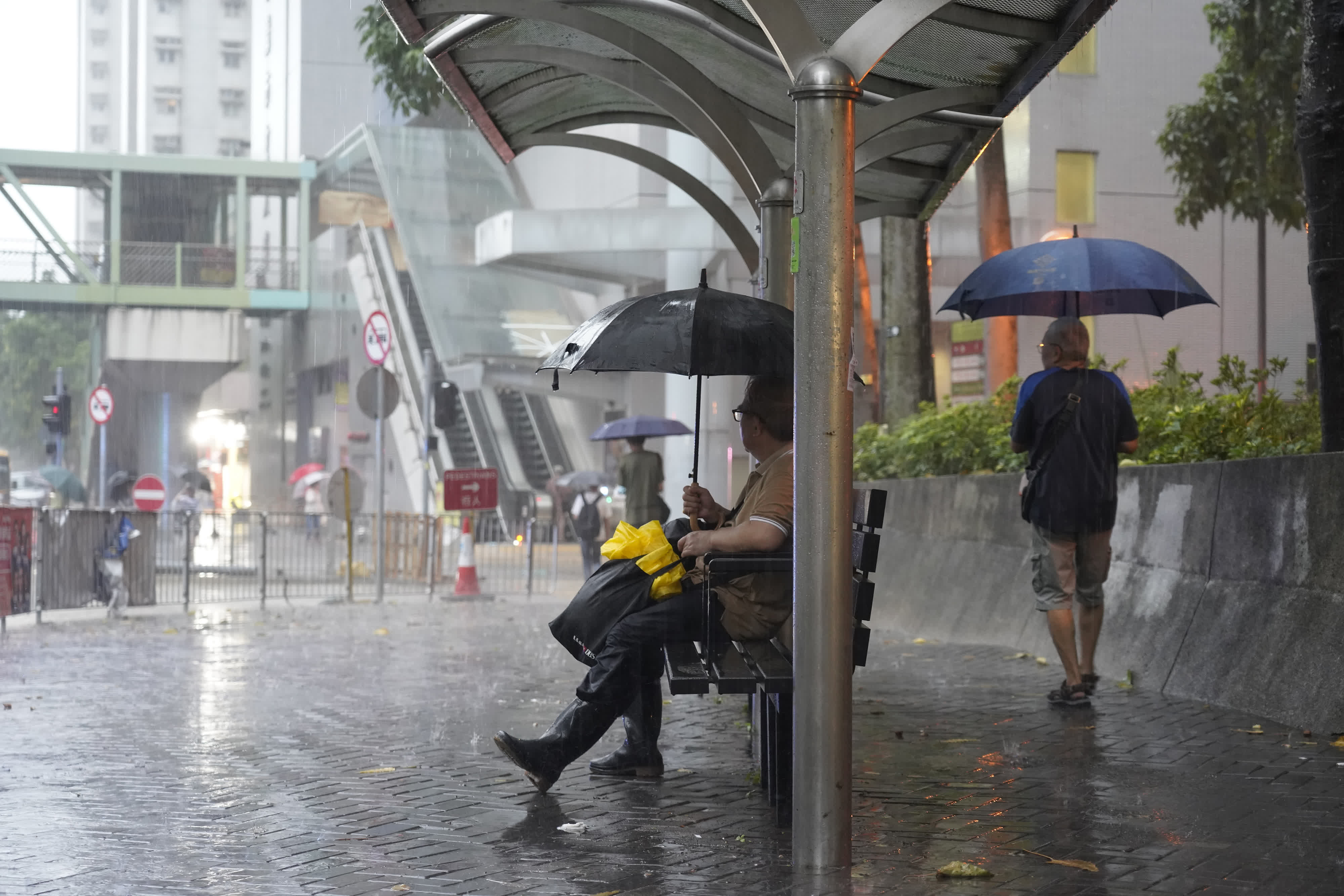 9月8日上午，港島柴灣地鐵站附近，市民在公交車站亭避雨。（中新社）