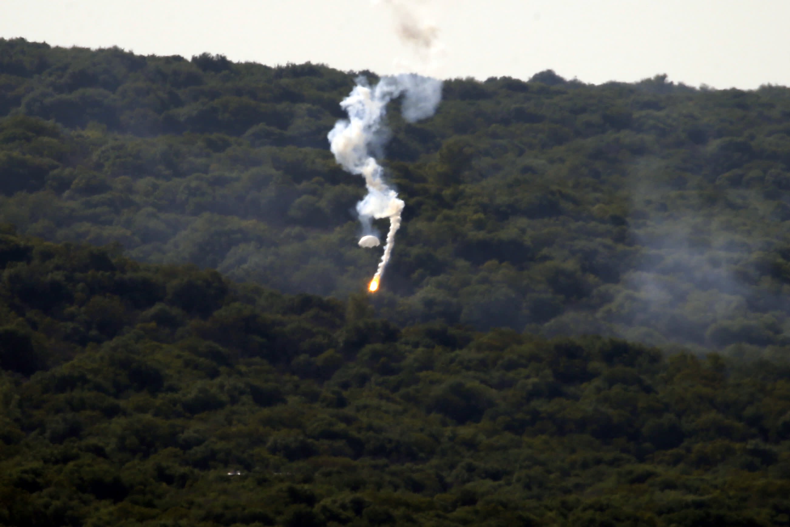 10月28日，閃光彈落在黎巴嫩納古拉樹林中燃起濃煙。（新華社）