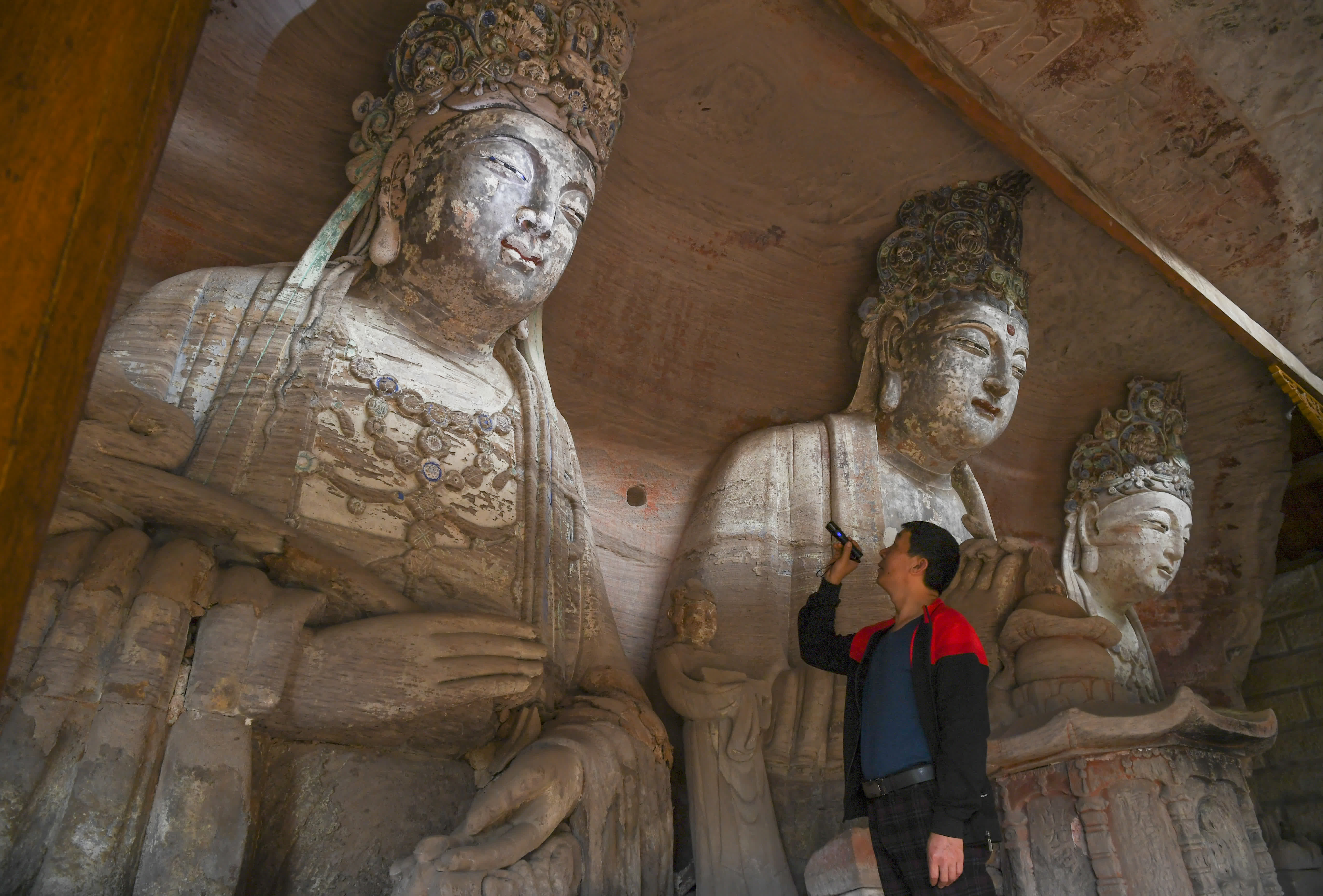 10月31日，在重慶市大足區寶頂鎮香山社區，義務文保員在對佛祖岩摩崖造像進行巡查。（新華社）