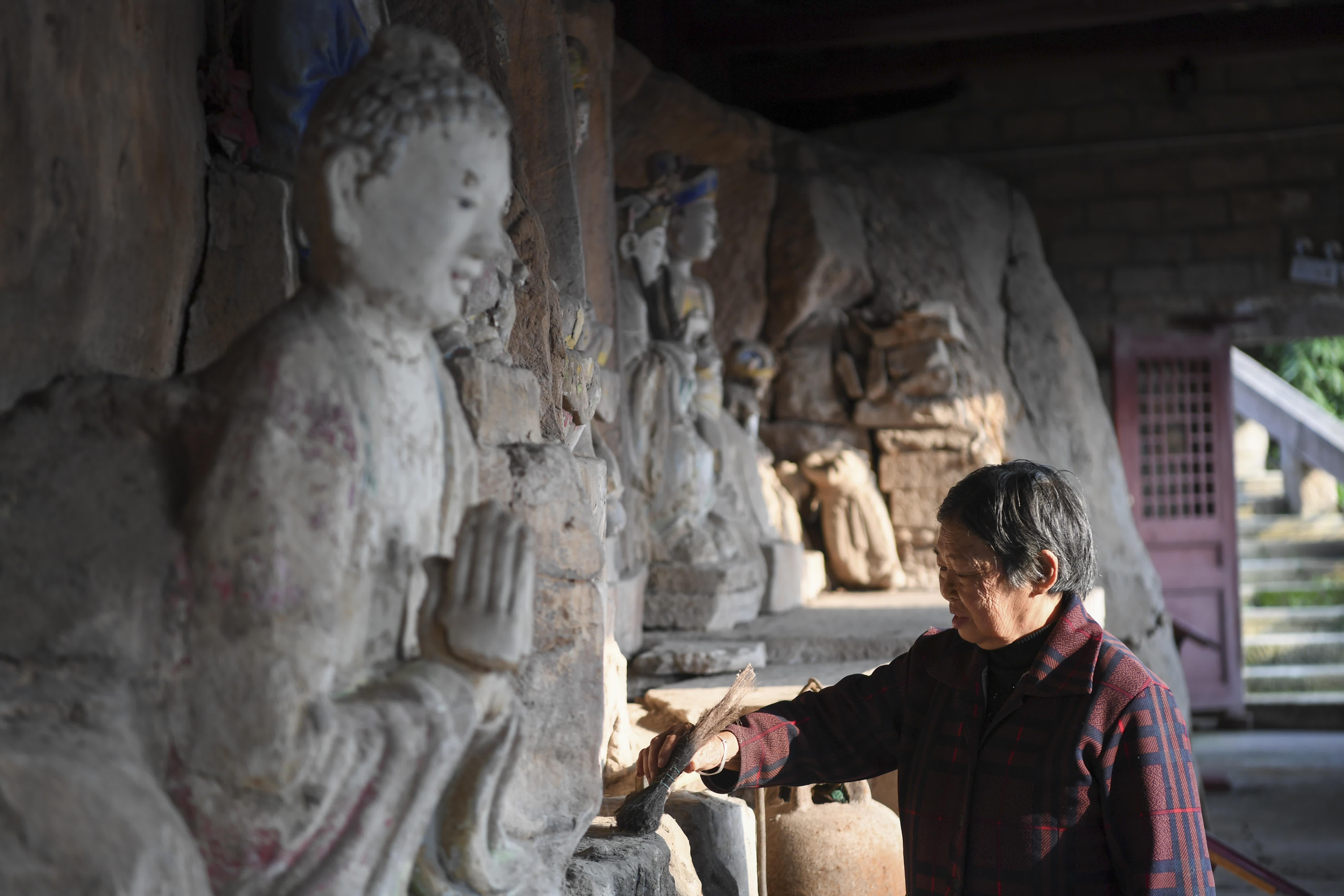 10月31日，在重慶市大足區中敖鎮金盆村，義務文保員在普聖廟摩崖造像文物保護點打掃衞生。（新華社）