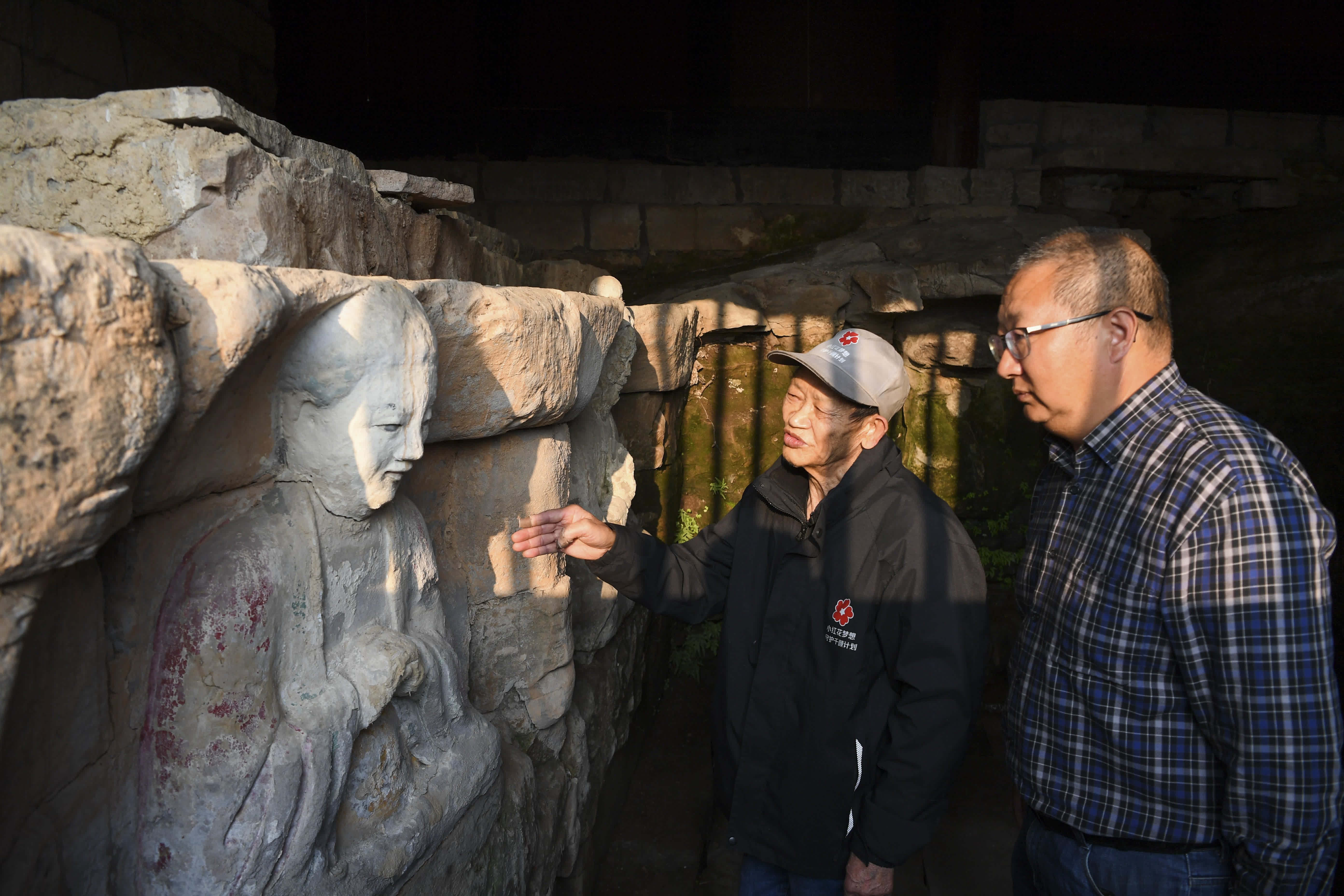  10月31日，在重慶市大足區中敖鎮金盆村，義務文保員（左）在向大足石刻研究院工作人員介紹普聖廟摩崖造像保護情況。（新华社）