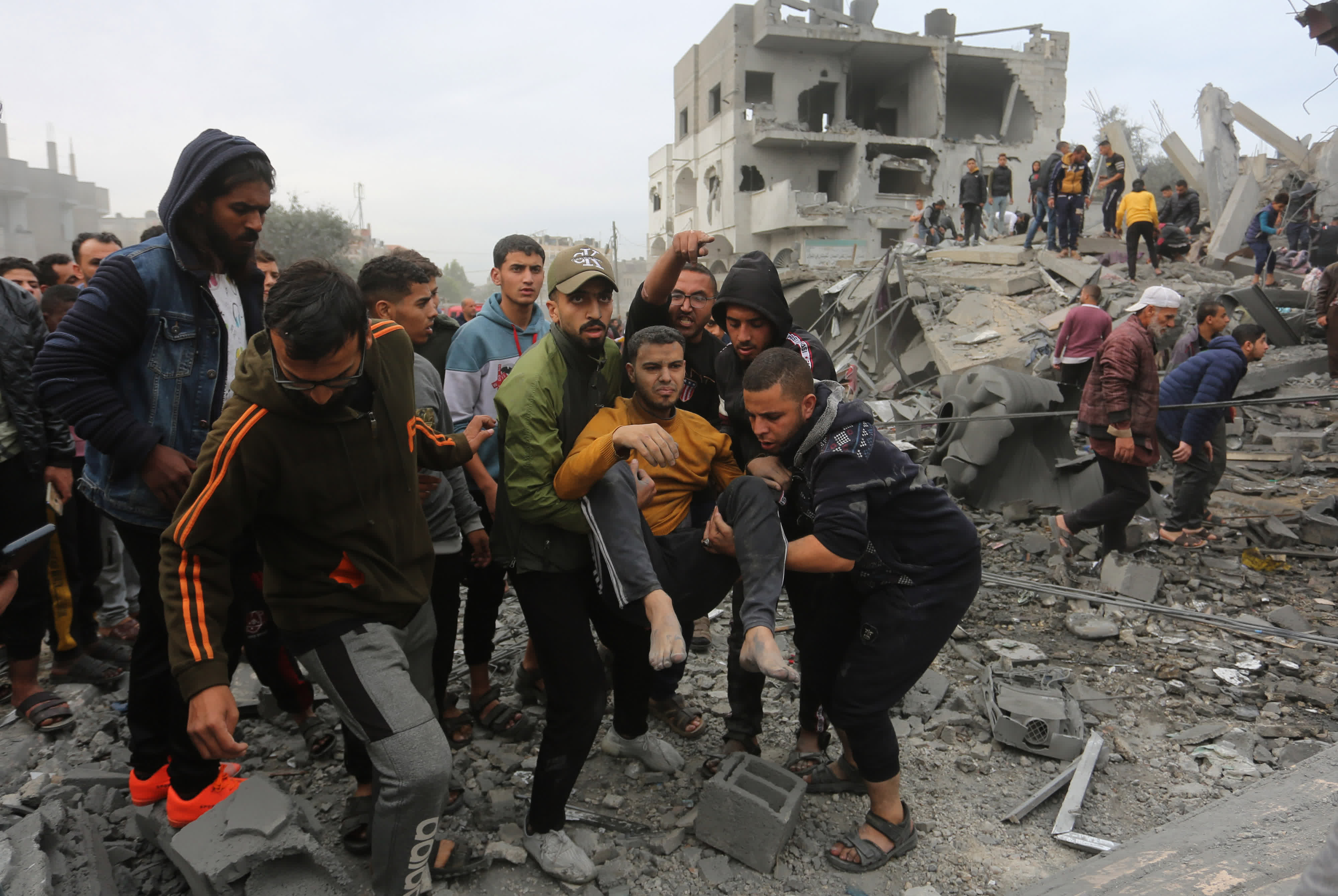  11月22日，人們在加沙地帶南部城市拉法的建築廢墟上實施救援。（新華社）