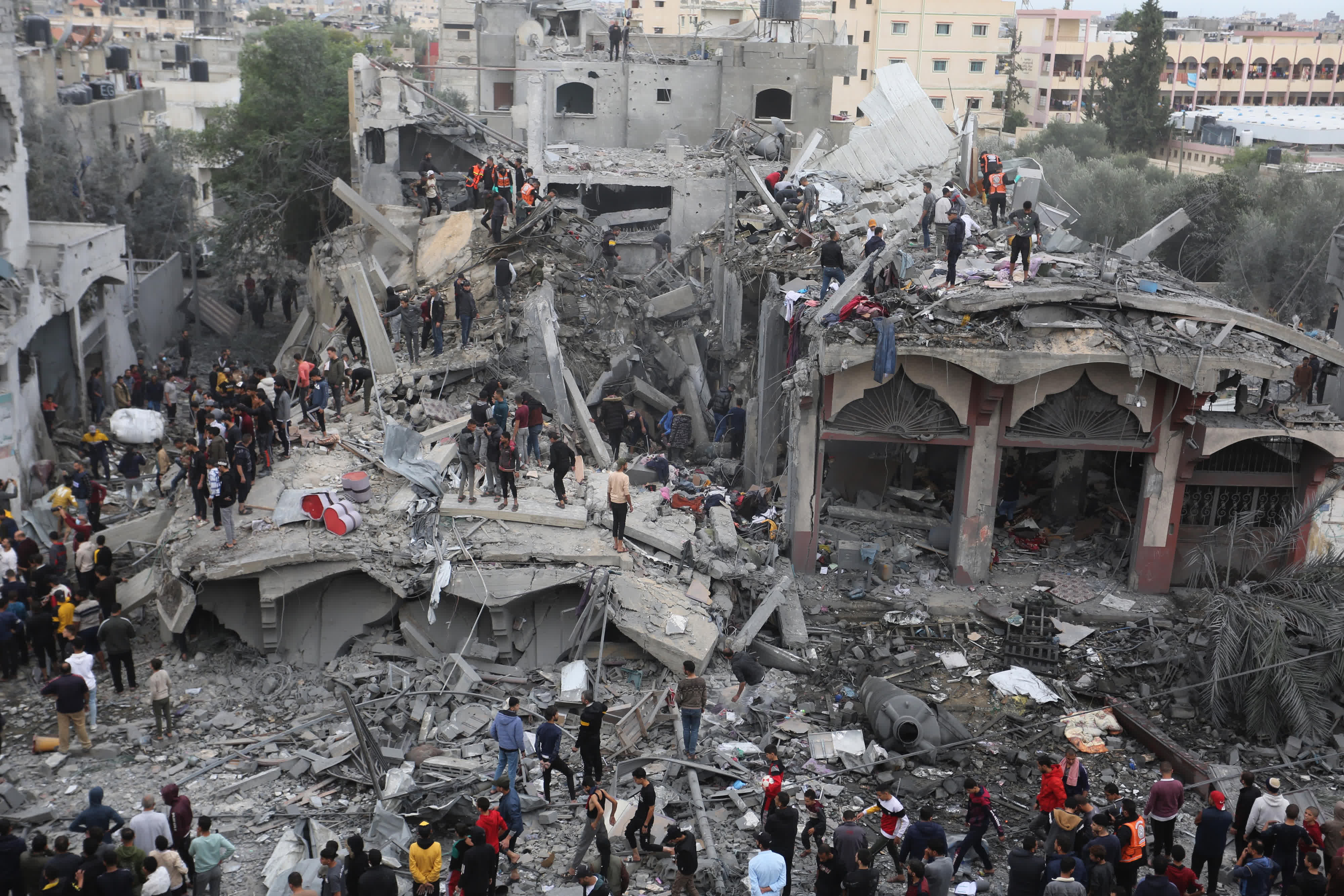 11月22日，人們在加沙地帶南部城市拉法的建築廢墟上實施救援。（新華社）