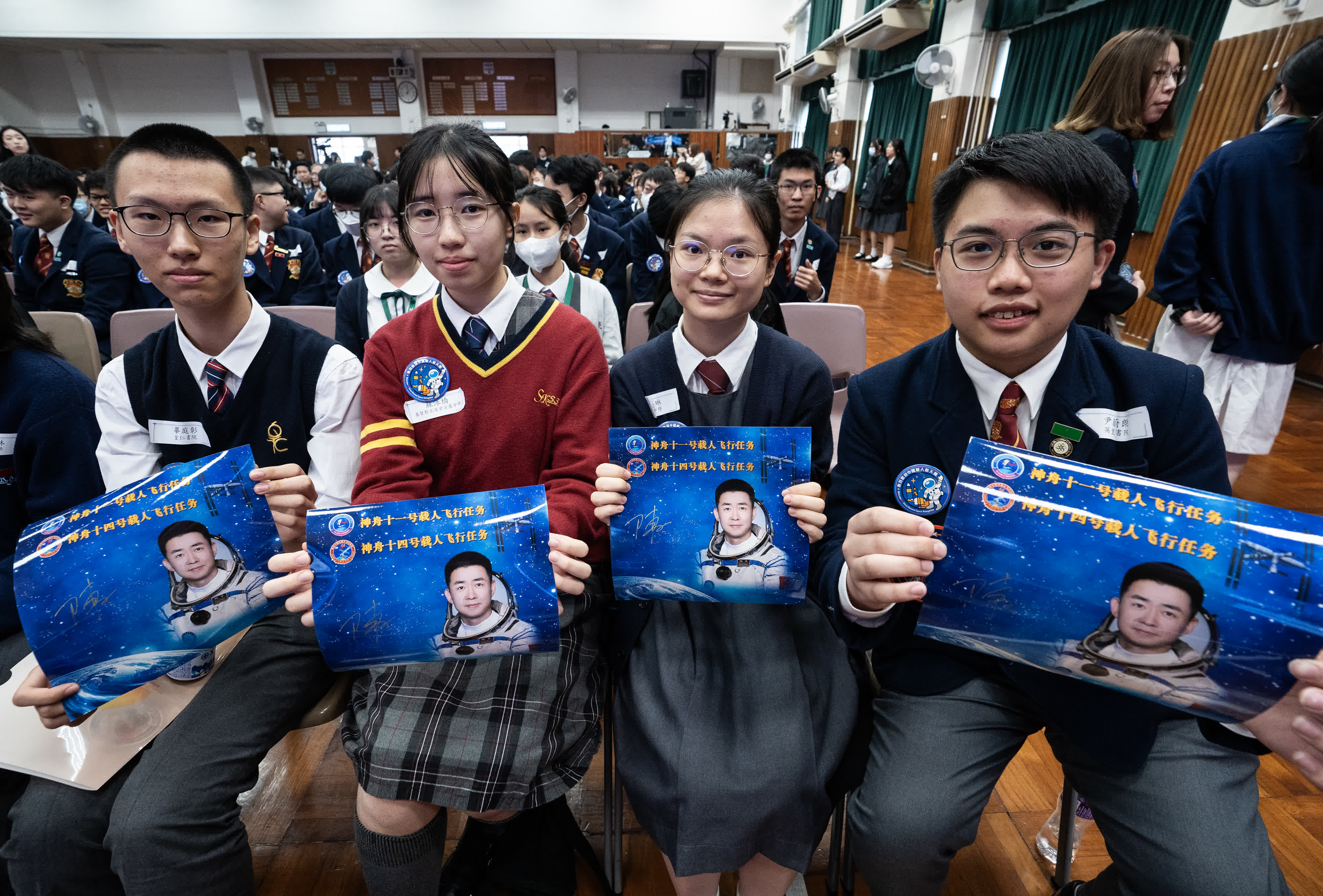 圖為學生們展示獲贈的航天員陳冬的簽名照片。 （中新社）
