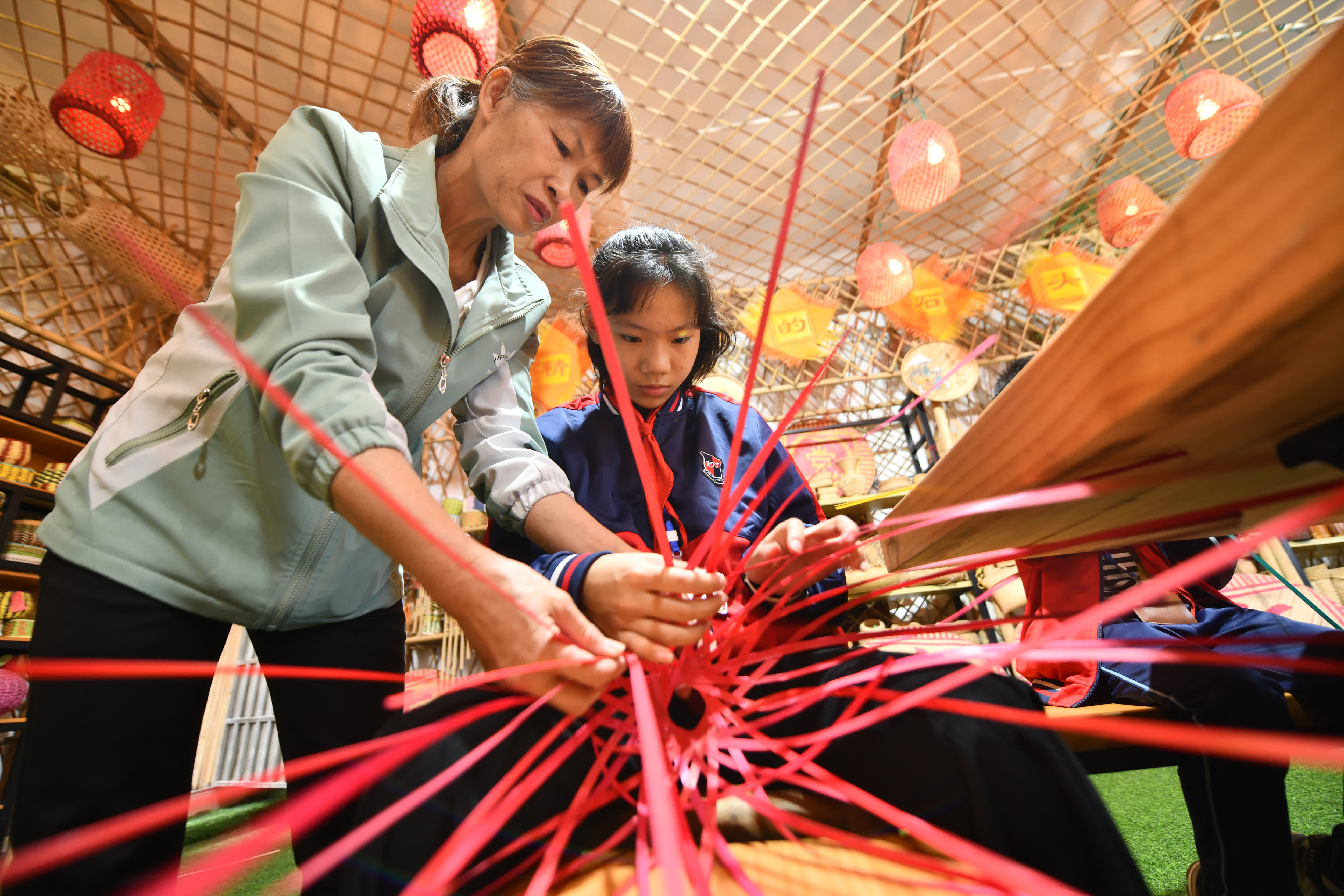 11月28日，在廣西岑溪市南渡中心小學，老師在指導小學生練習竹芒編織技藝。（新華社）